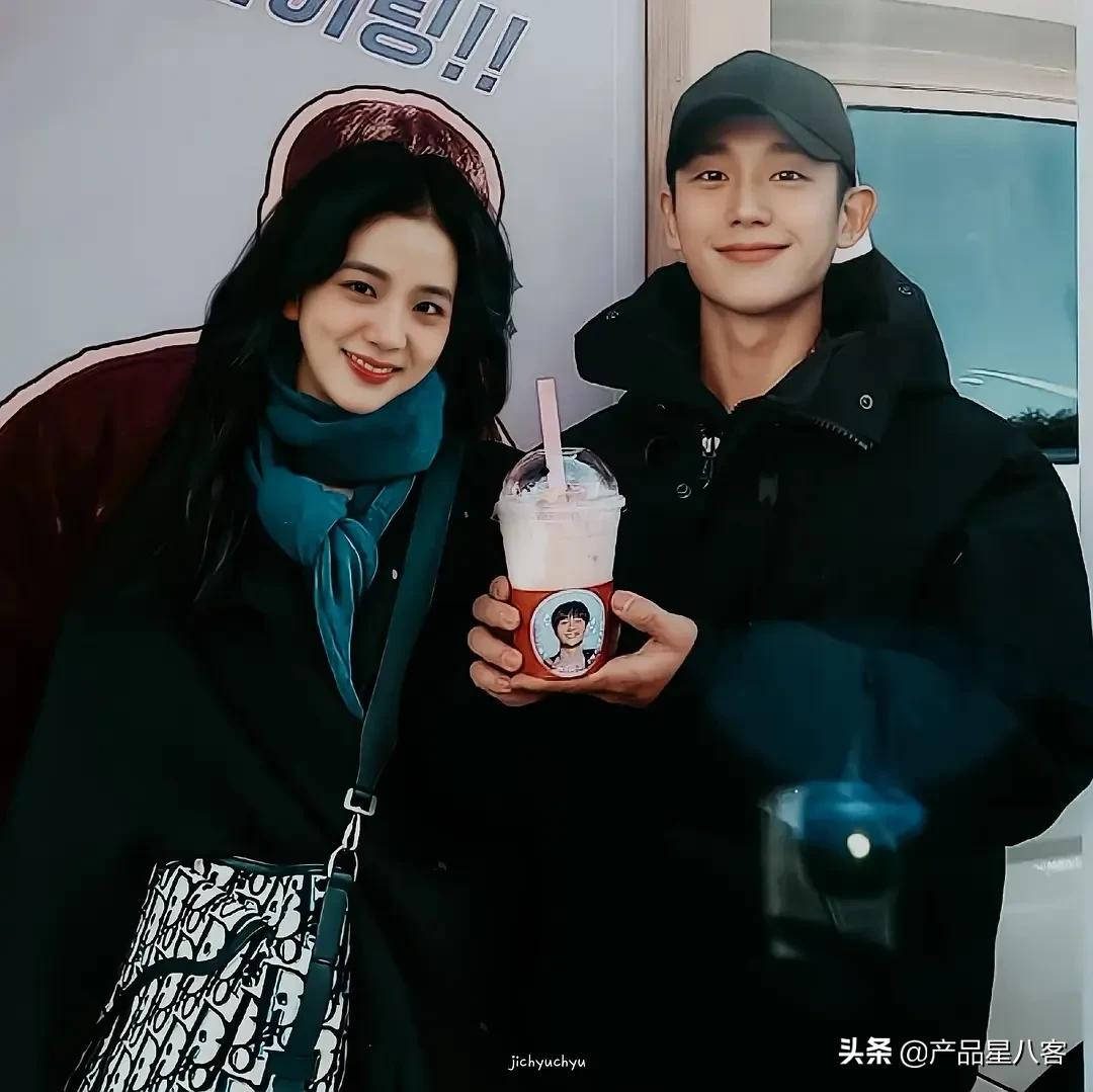 《雪滴花》劇中主角CP 壁紙 — 一對微笑的年輕情侶穿著冬季外套，一起拿著帶有卡通貼紙的品牌奶昔擺姿勢。