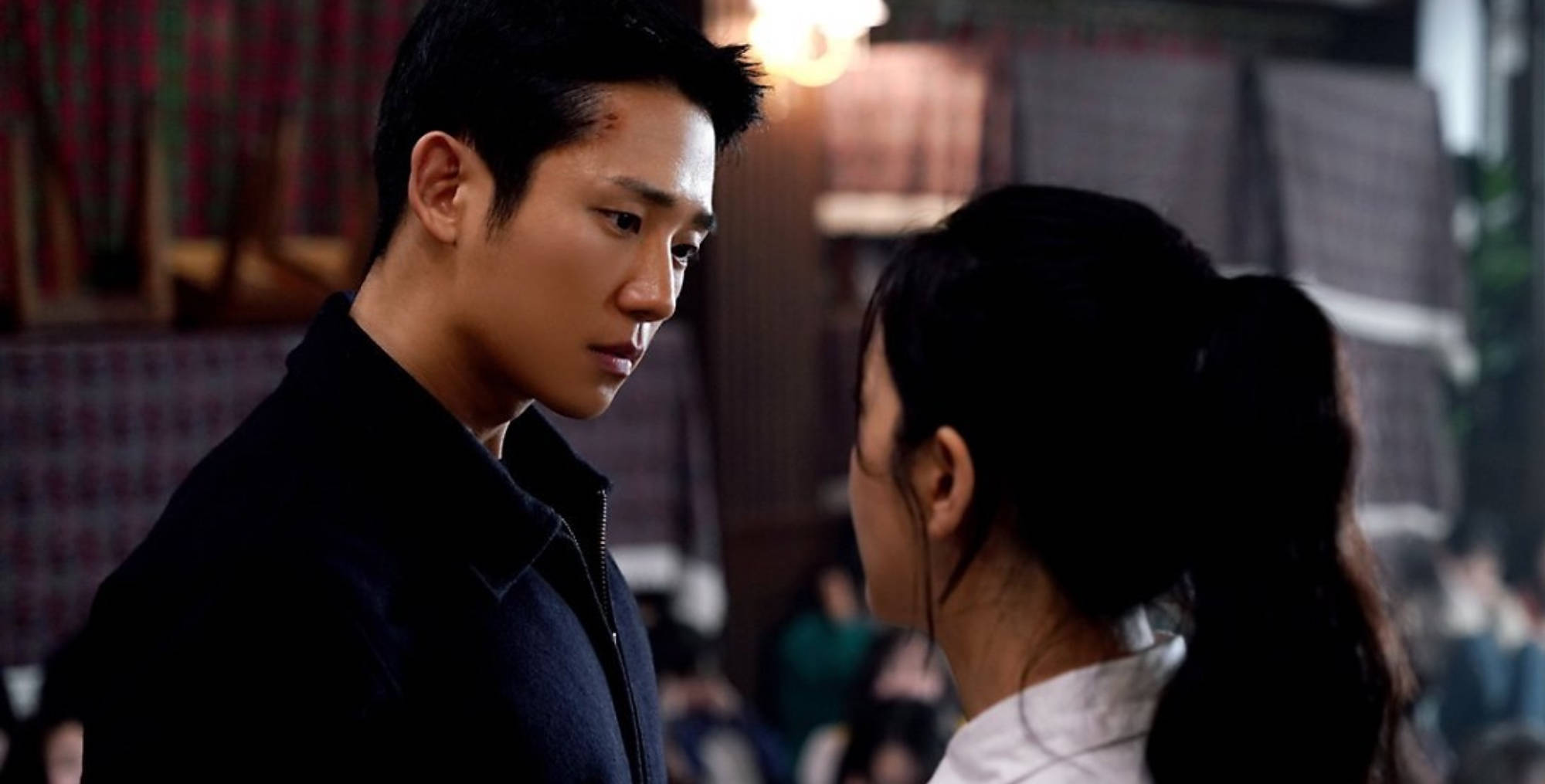《雪滴花》劇中帥氣Jung Hae-In 壁紙 — 一名額頭有傷口的男子在昏暗的室內環境中專注地凝視著一名紮馬尾的女子。