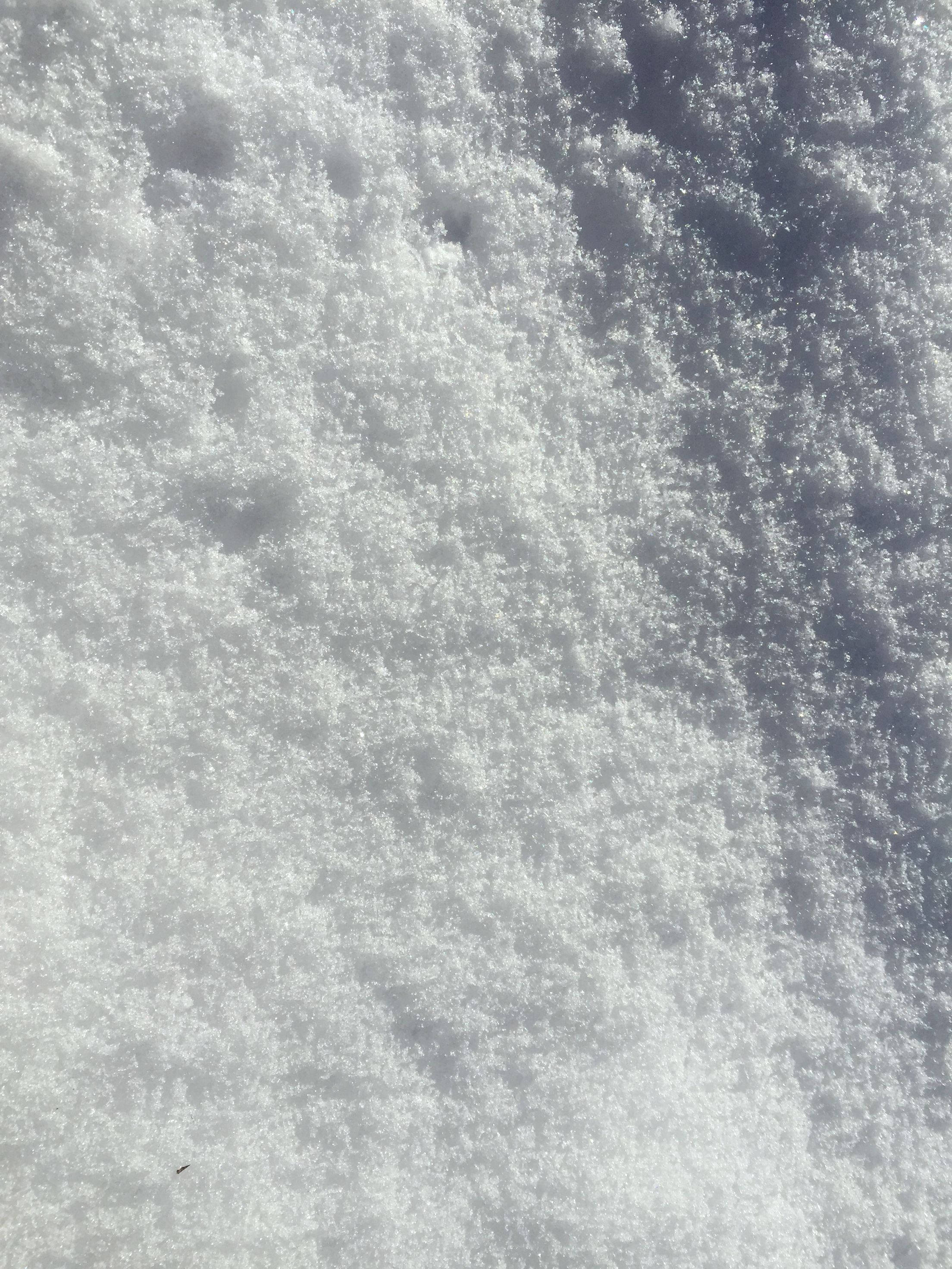 雪白紋理 壁紙 — 特寫紋理雪地，陽光照射的晶體和柔和陰影營造寧靜的冬季場景。