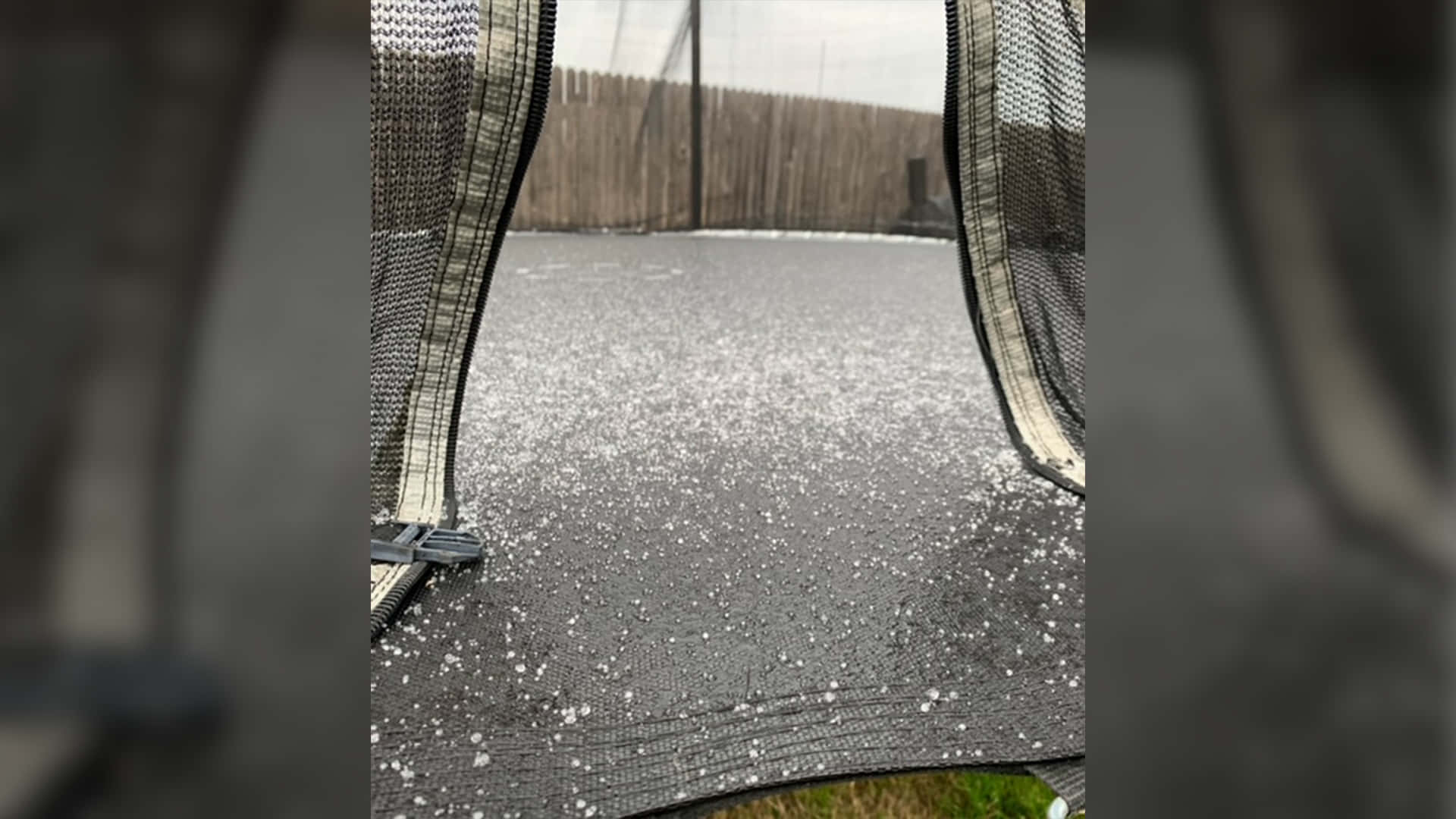 雪花飄落地面 壁紙 — 彈床表面近景，上面散落著雪花，背景是木柵欄。