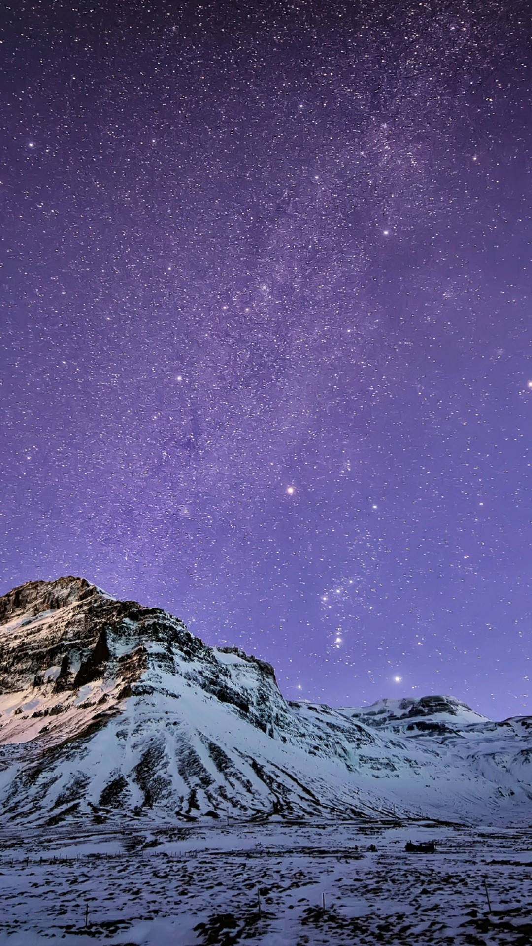 雪覆岩石山丘 iPhone 8 動態背景 壁紙 — 白雪覆蓋的山峰在充滿無數星星和銀河的 vibrant 紫色夜空下升起。