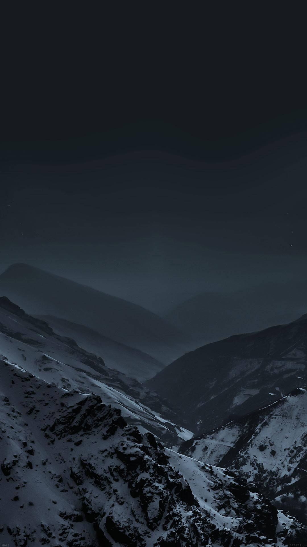 雪覆暗山 iPhone 6s Plus 壁紙 — 一個嚴酷的冬季山谷，在繁星點點的夜空下，積雪依附在崎嶇的山峰和霧氣繚繞的山脊上。