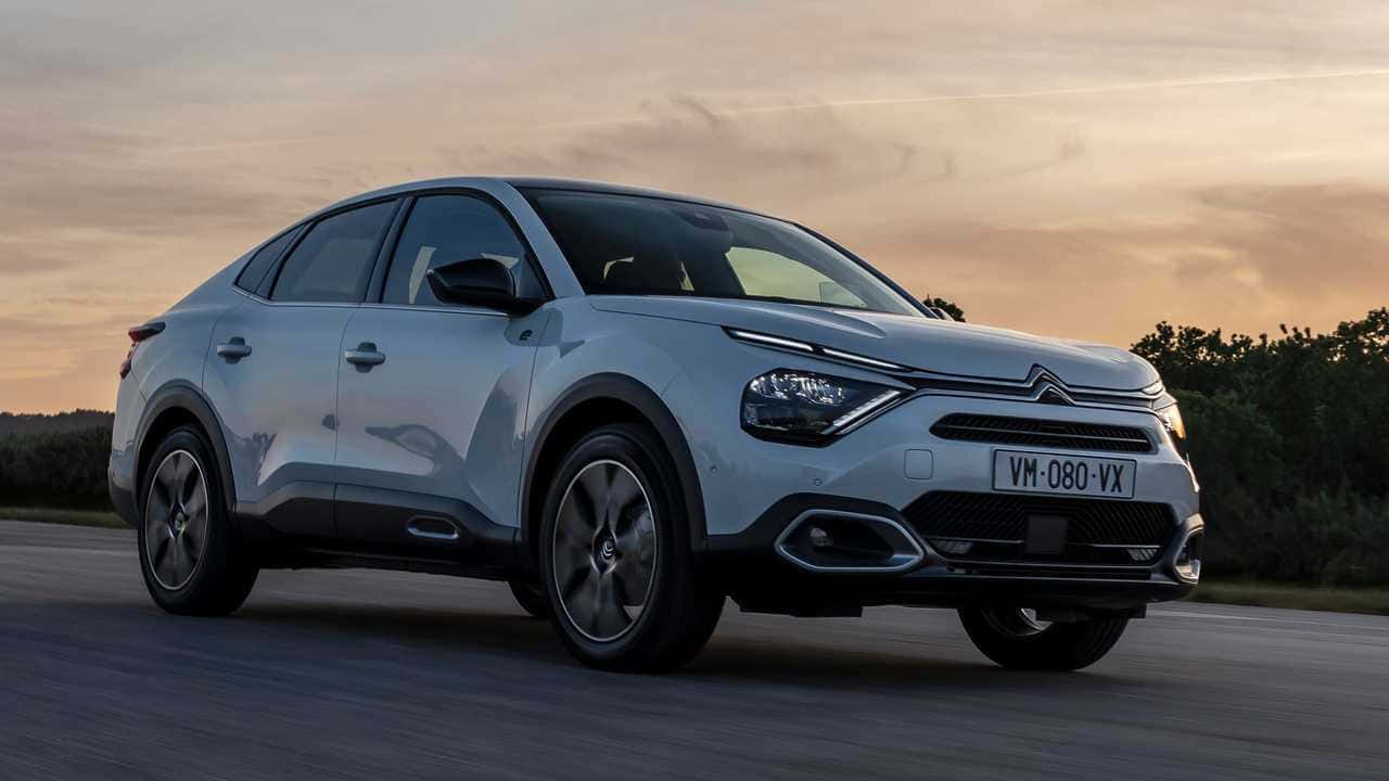 雪鐵龍DS High Rider 黃昏駕駛 壁紙 — 一輛時尚的銀色雪鐵龍 C5 Aircross SUV 在日落時分沿著道路行駛，溫暖的金色光芒投下長長的影子。
