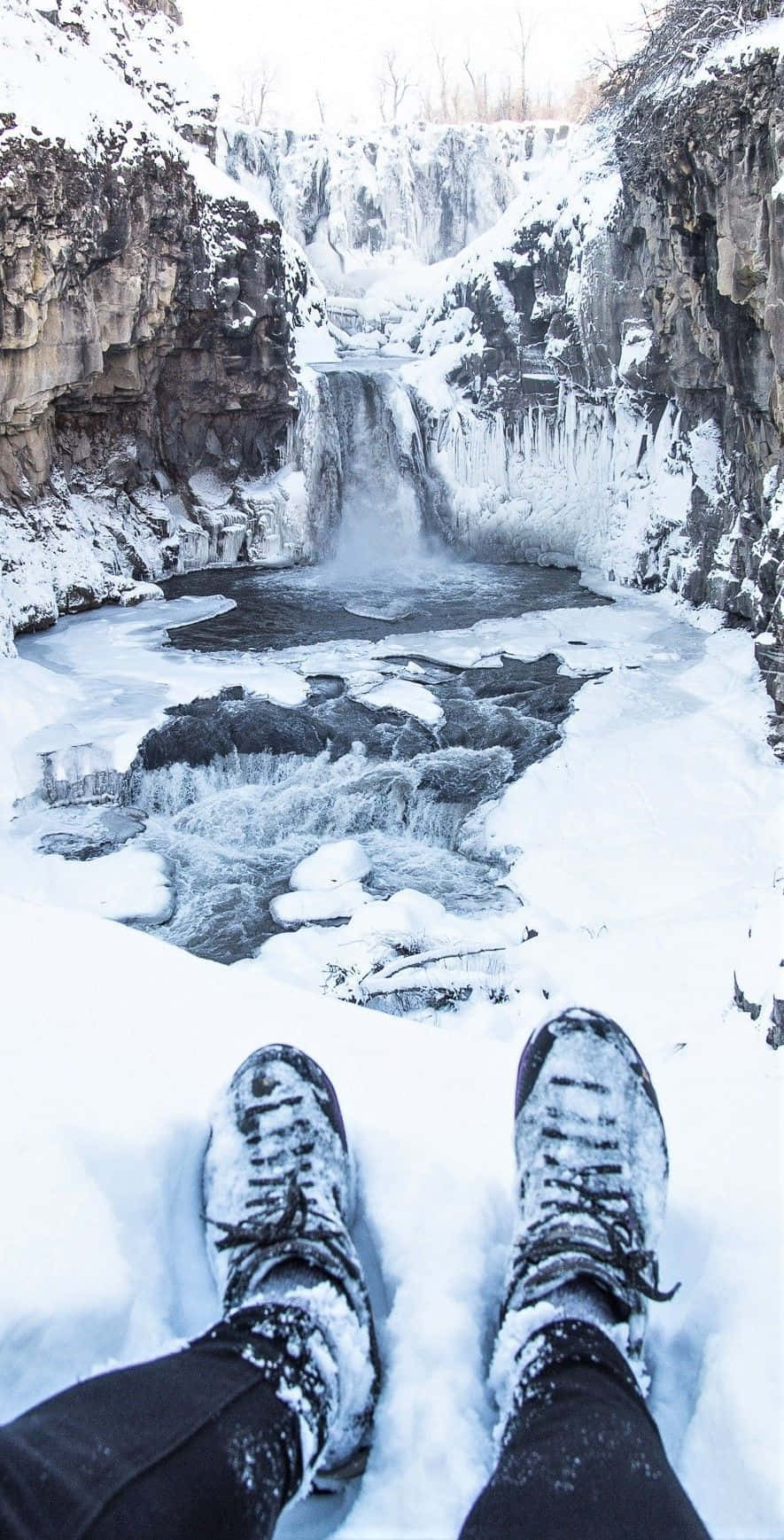 Winter Hiking 桌布 壁紙 — 雪靴擱在冬季冰瀑邊緣，冰瀑從冰崖傾瀉而下。