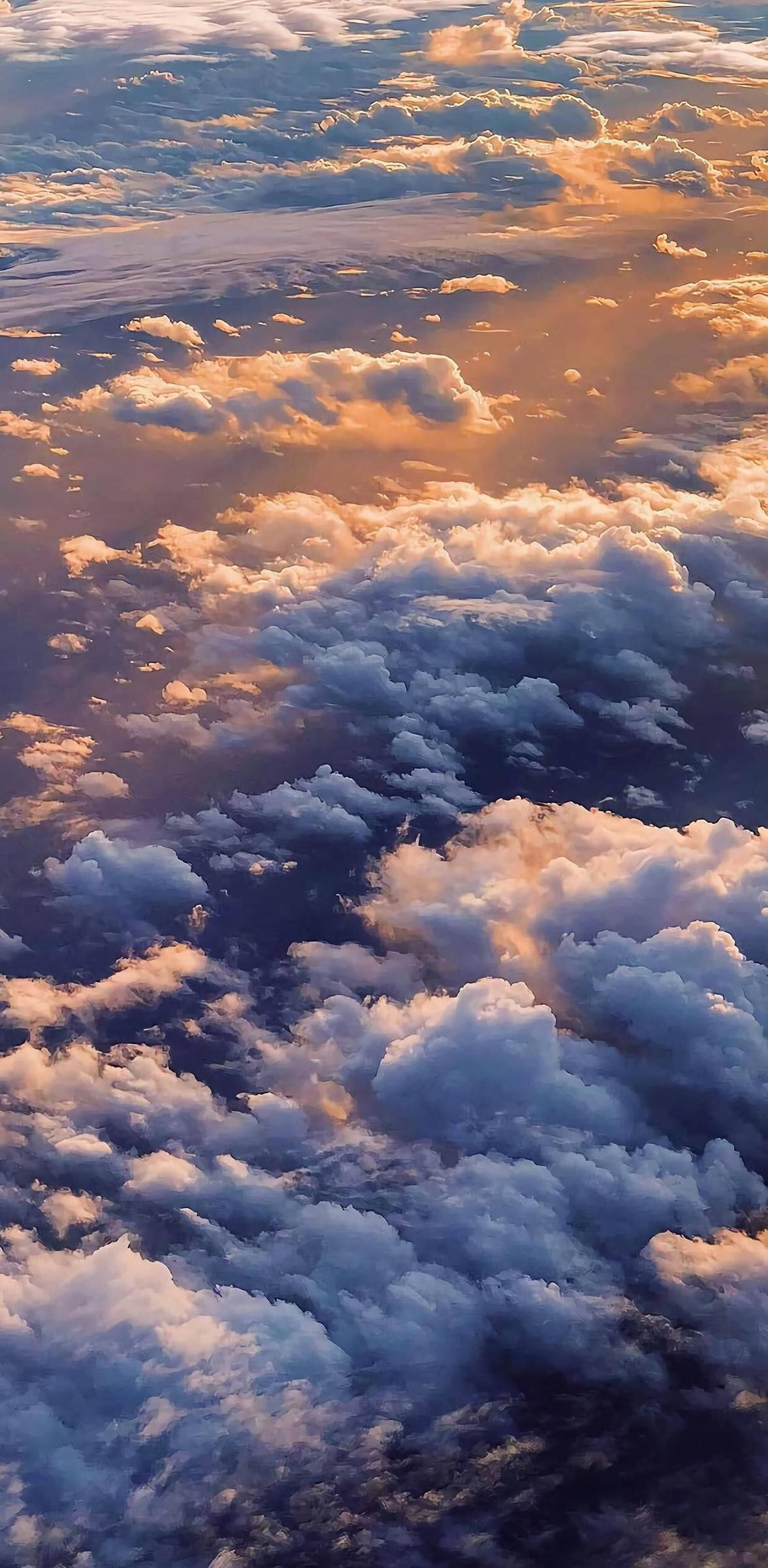 雲上 iPhone 12 壁紙 — 從高空俯瞰蓬鬆的雲朵沐浴在金色夕陽光中，下方是深藍色的陰影。