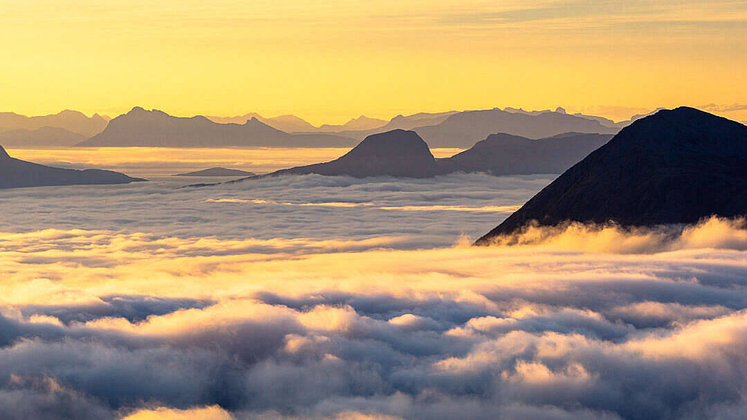 山峰在日出時升起在雲海之上，沐浴在金色光芒中。