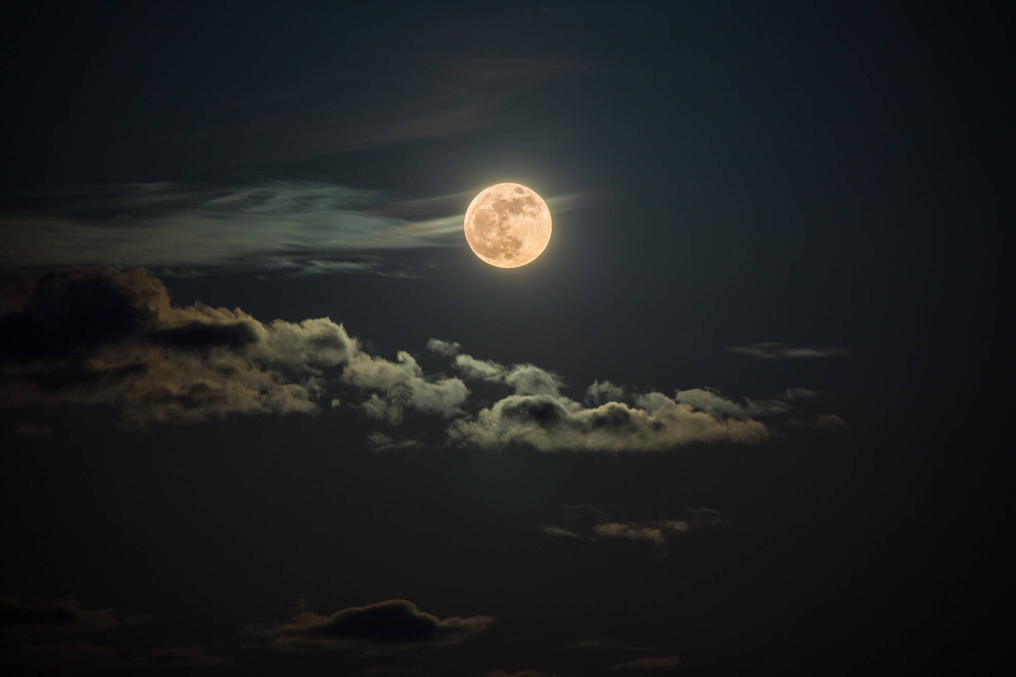 雲夜中的唯美月色 壁紙 — 一輪明亮的滿月透過散落的雲層在深邃的夜空中發光。