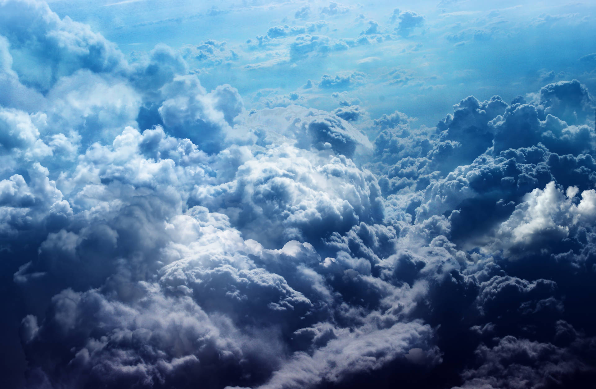 雲層之上的美麗天空 壁紙 — 廣闊的棉花狀雲朵在深淺藍色調中，在明亮的天空下無盡延伸。