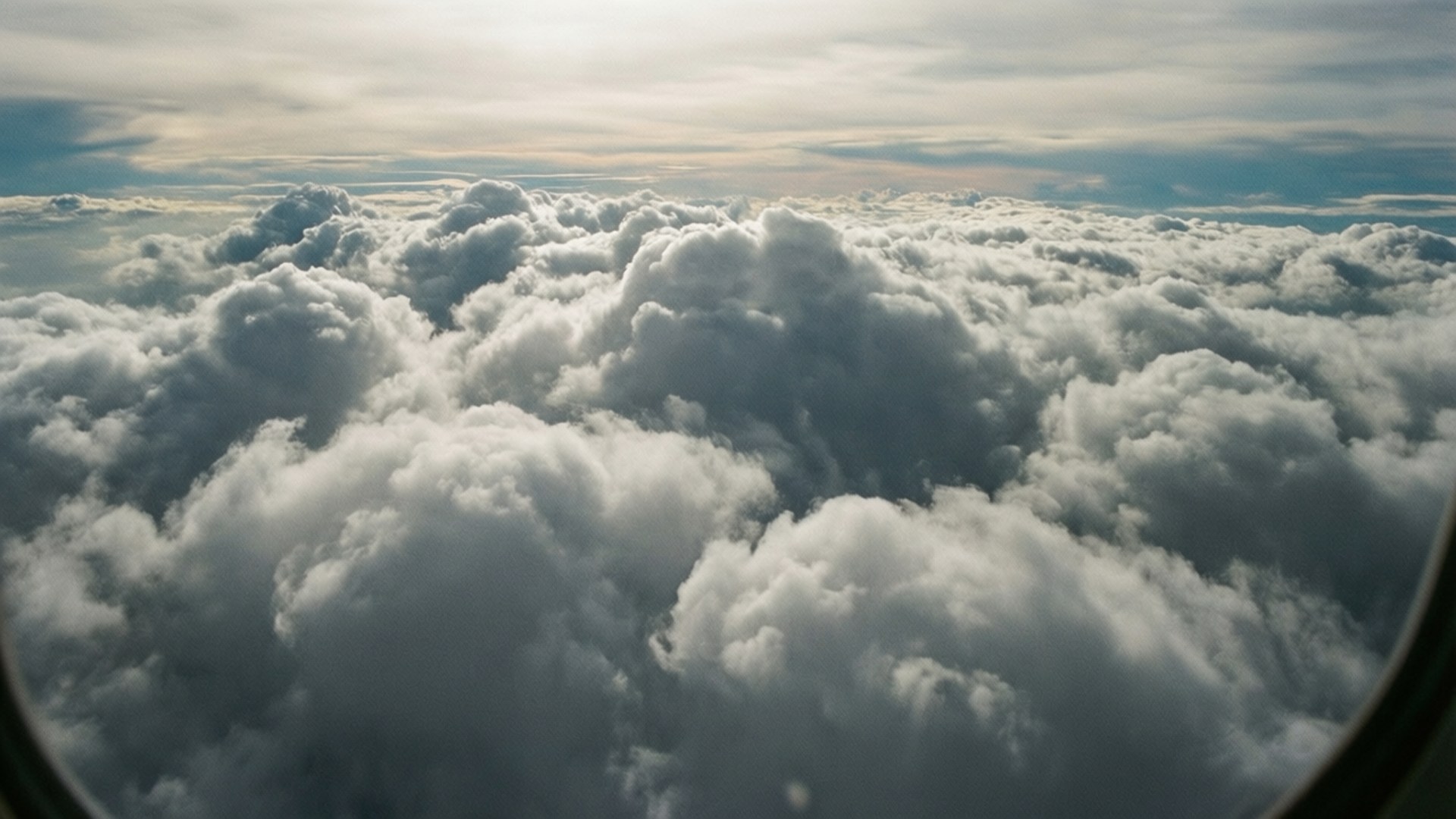 從飛機窗戶看到的蓬鬆白雲景色，上方金色天空