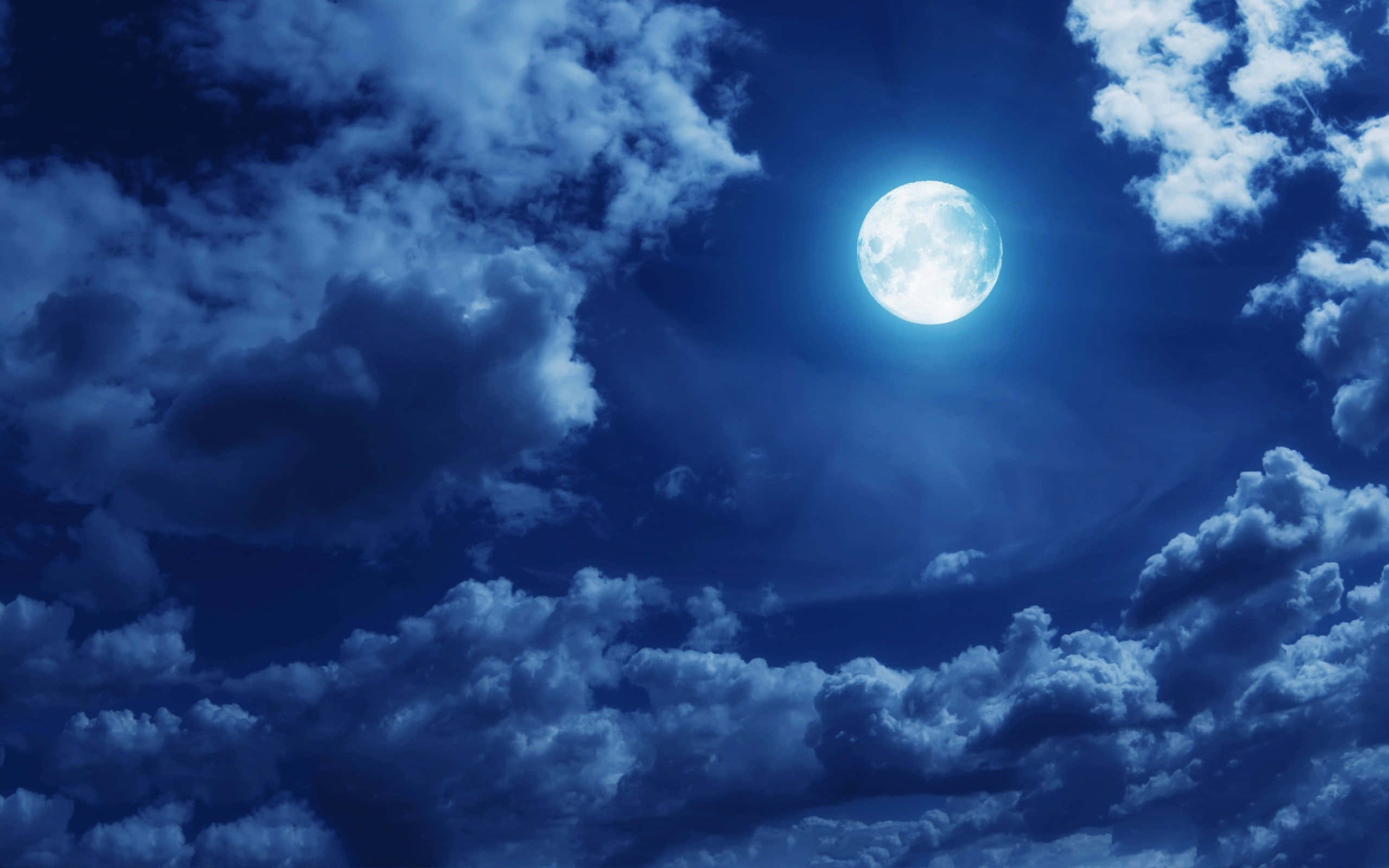 雲層藍夜月圖 壁紙 — 一輪明亮的滿月在深靛藍色夜空中，穿過戲劇性旋轉的雲層閃耀。