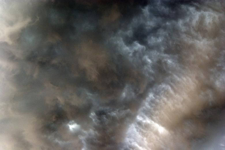 濃密旋轉的雲層呈現灰色和米色，柔和光線穿透