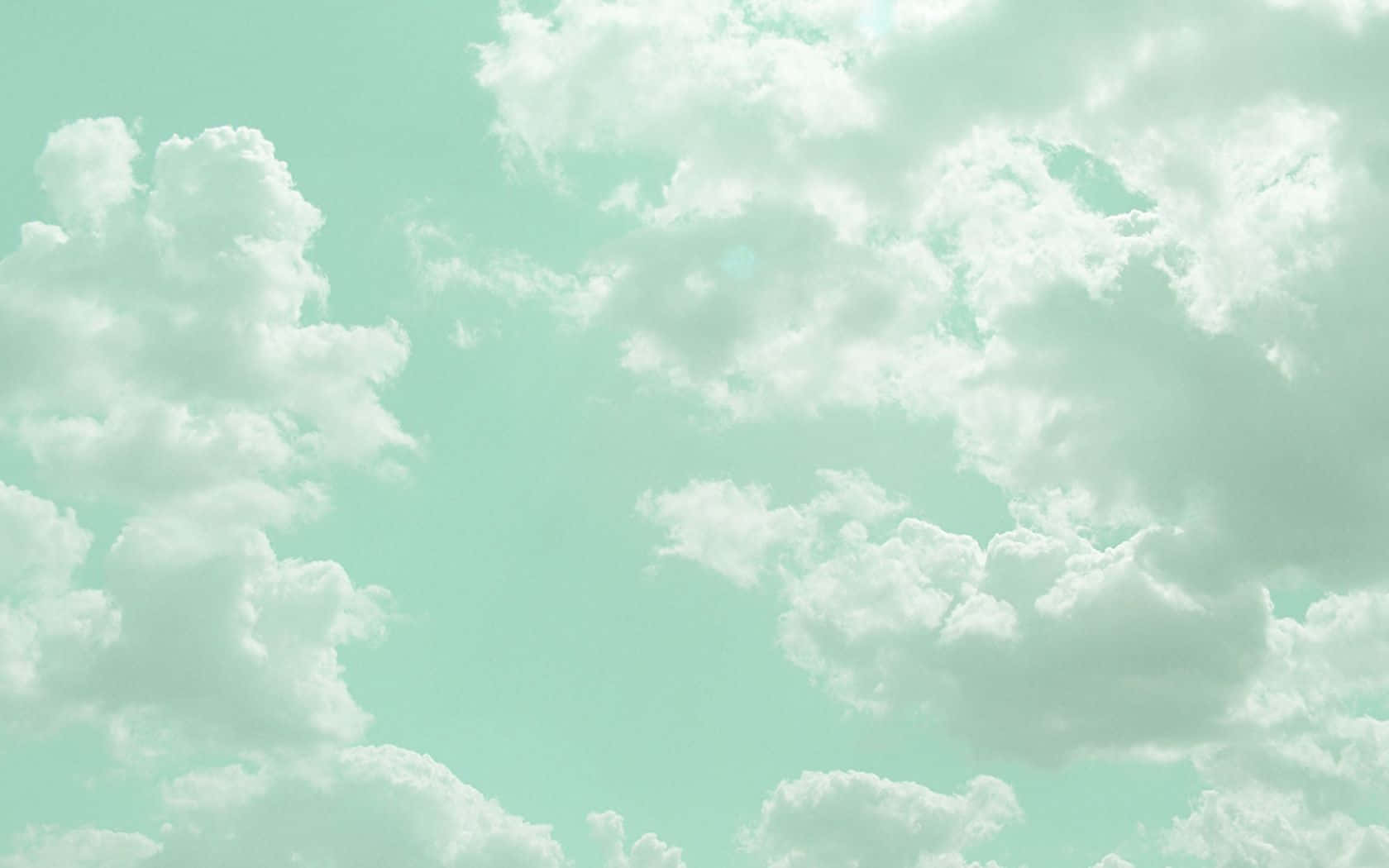 雲景攝影柔和綠色美學桌面 壁紙 — 柔軟的棉花狀雲朵懶洋洋地飄過寧靜的薄荷綠色天空，構成寧靜的日間場景。