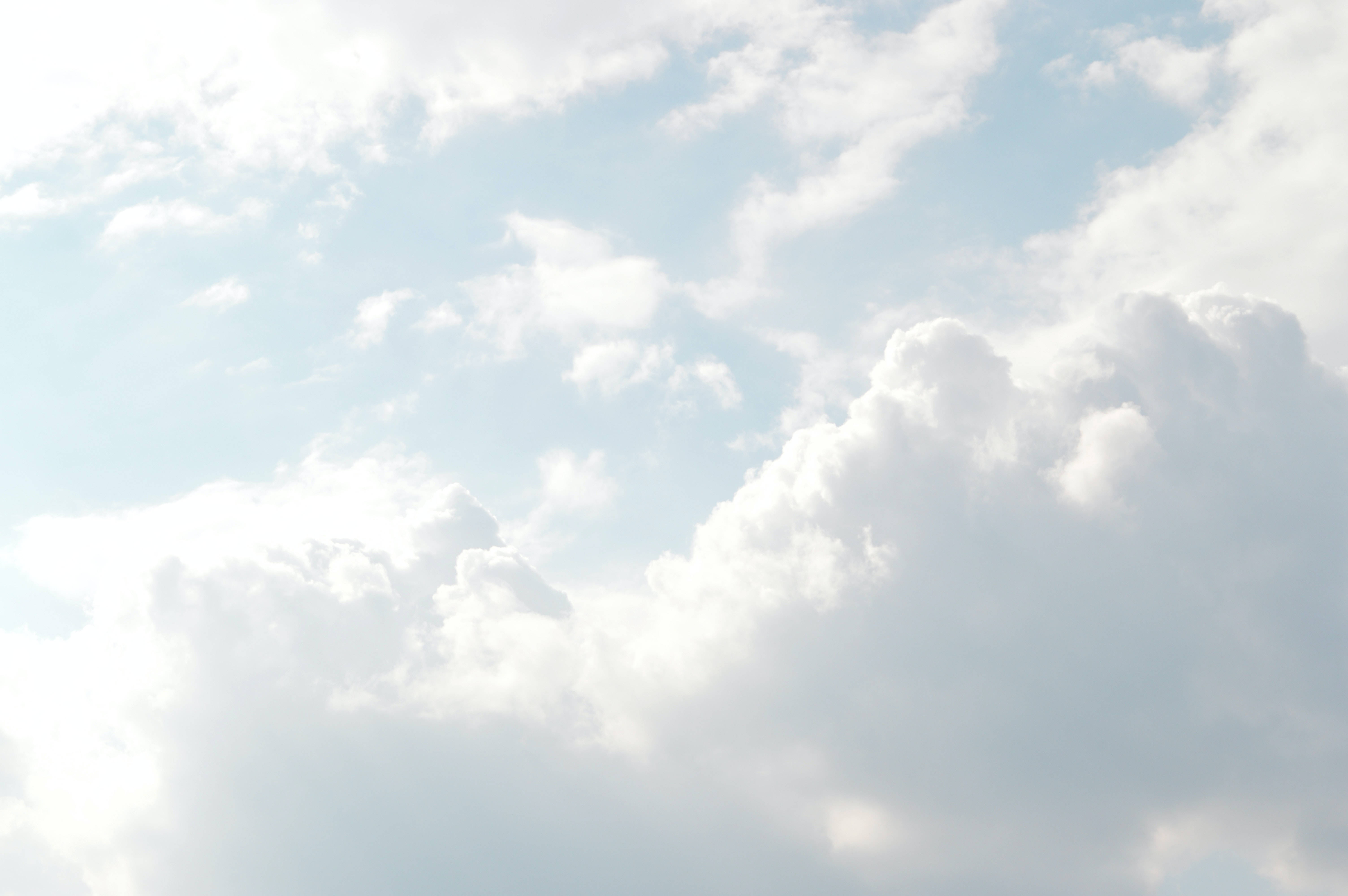 雲朵天空明亮背景 壁紙 — 廣闊的天空中，柔軟的白雲在明亮的日光下飄過淡藍色的畫布。