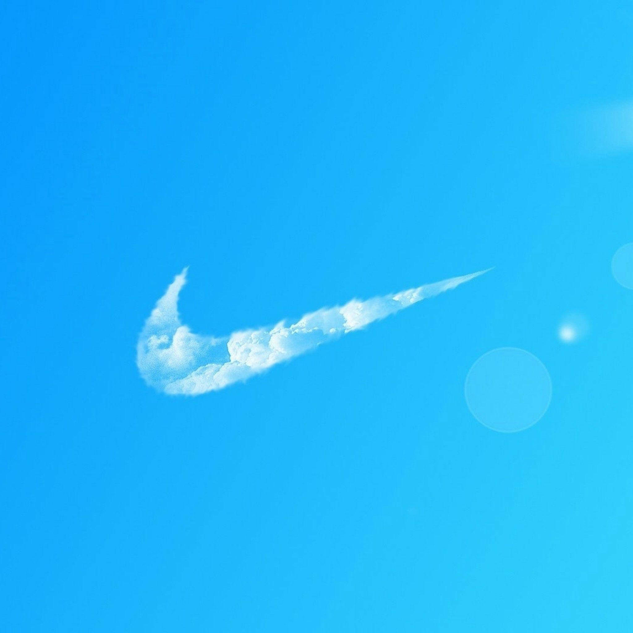 雲朵造型耐克 iPhone 標誌 壁紙 — 一朵白色雲朵形狀像Nike勾號，在清澈的藍天中飄浮，帶有柔和鏡頭光暈。
