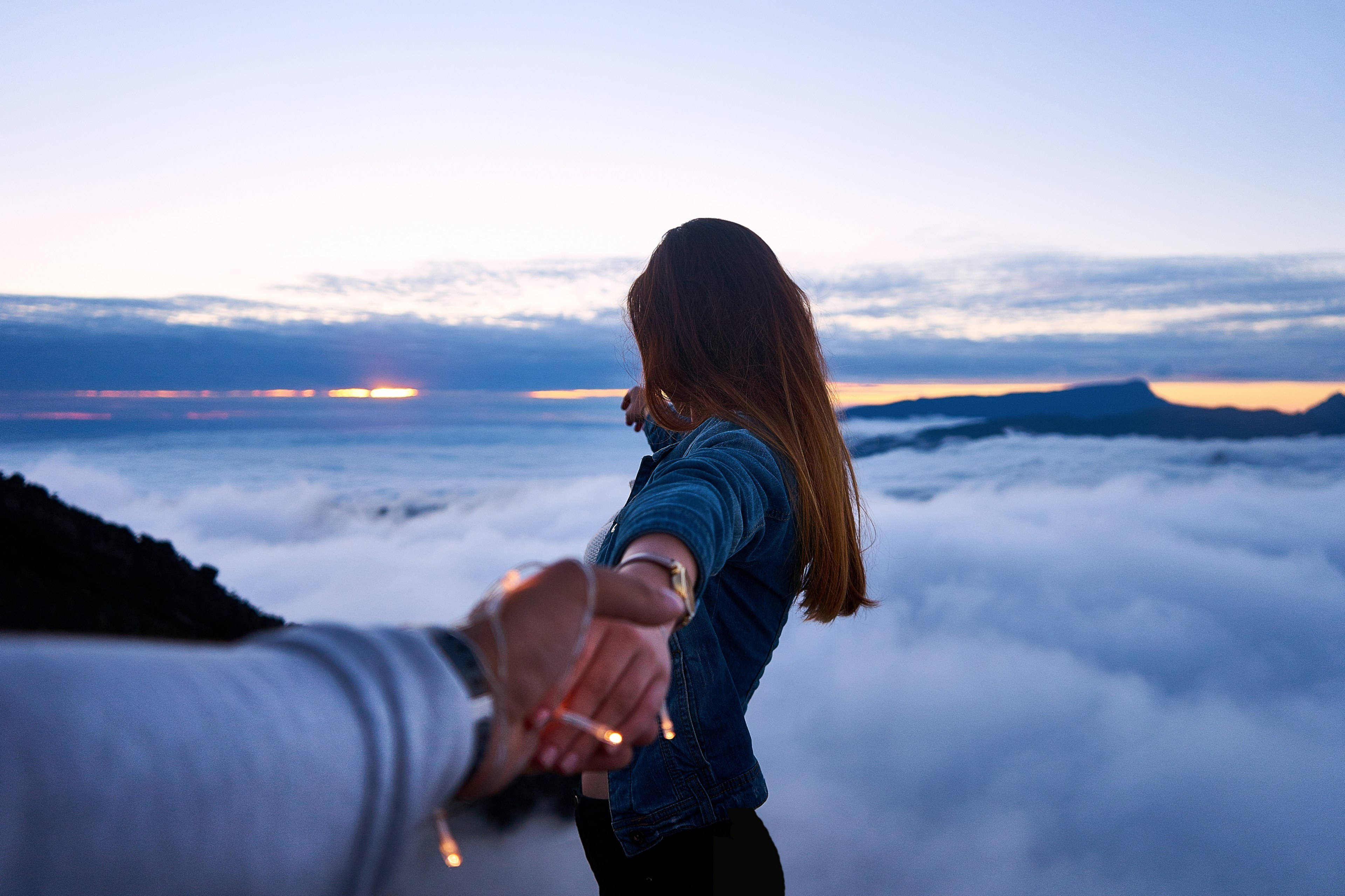 雲海中牽手 壁紙 — 一個人與一位站在日出時雲海之上、遠山相伴的女子牽手。