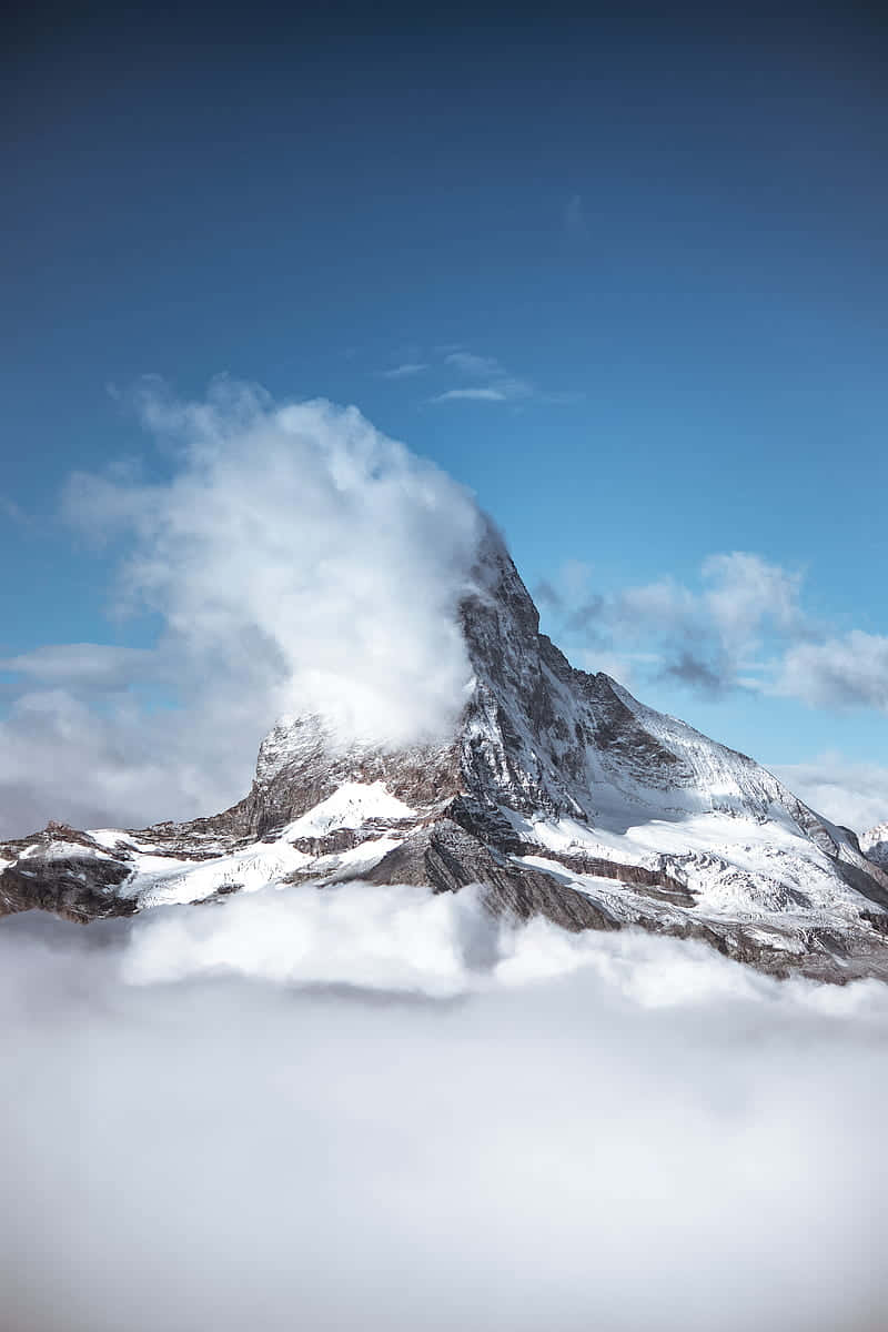雲海之上的雄偉雪山 壁紙 — 雄偉的雪山峰頂在清澈的藍天下穿過蓬鬆的白雲。
