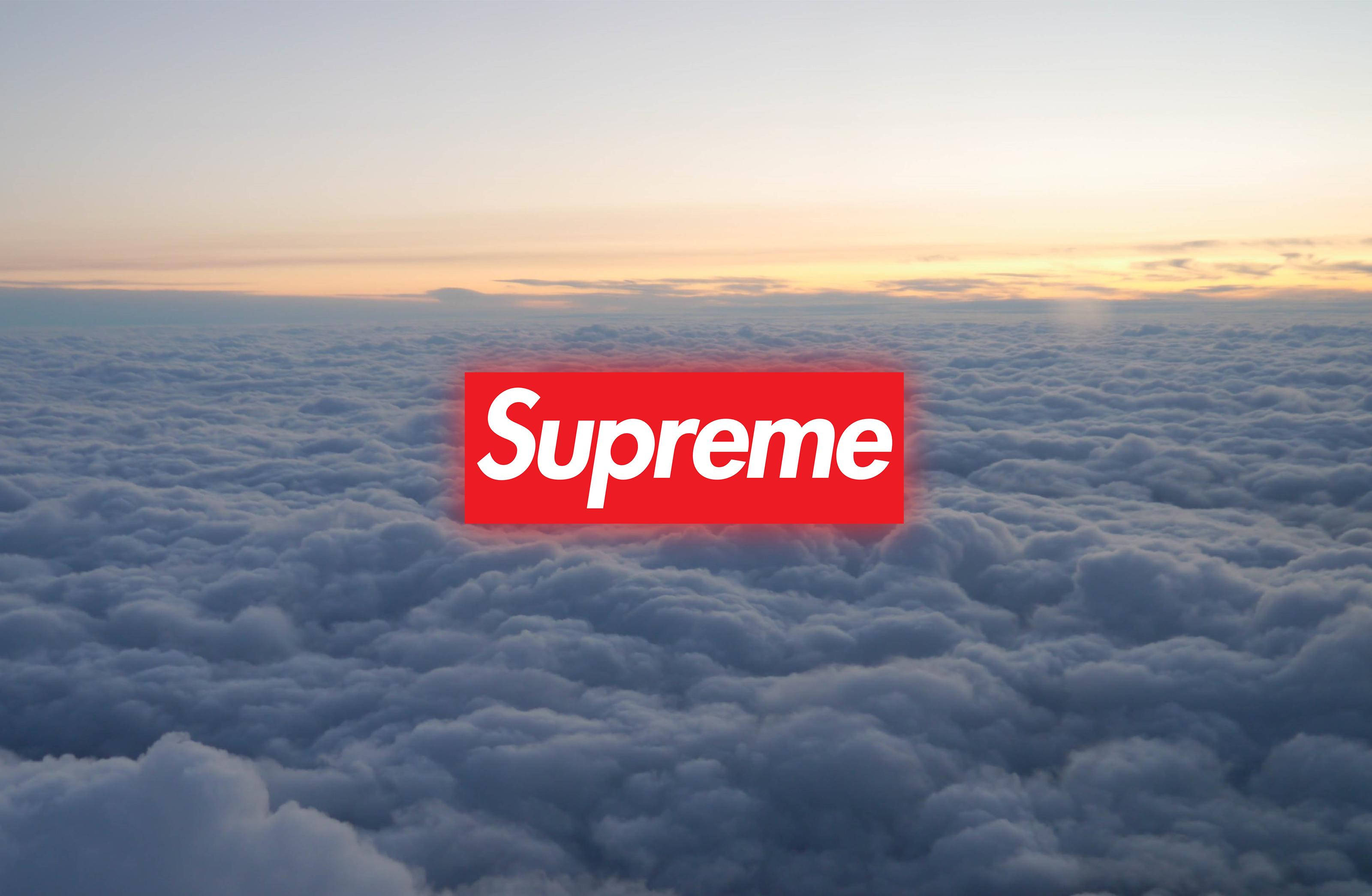 雲海背景上的 Supreme 標誌 壁紙 — 日出時分，紅色Supreme標誌漂浮在雲海之上，帶有柔和的橙色和藍色色調。