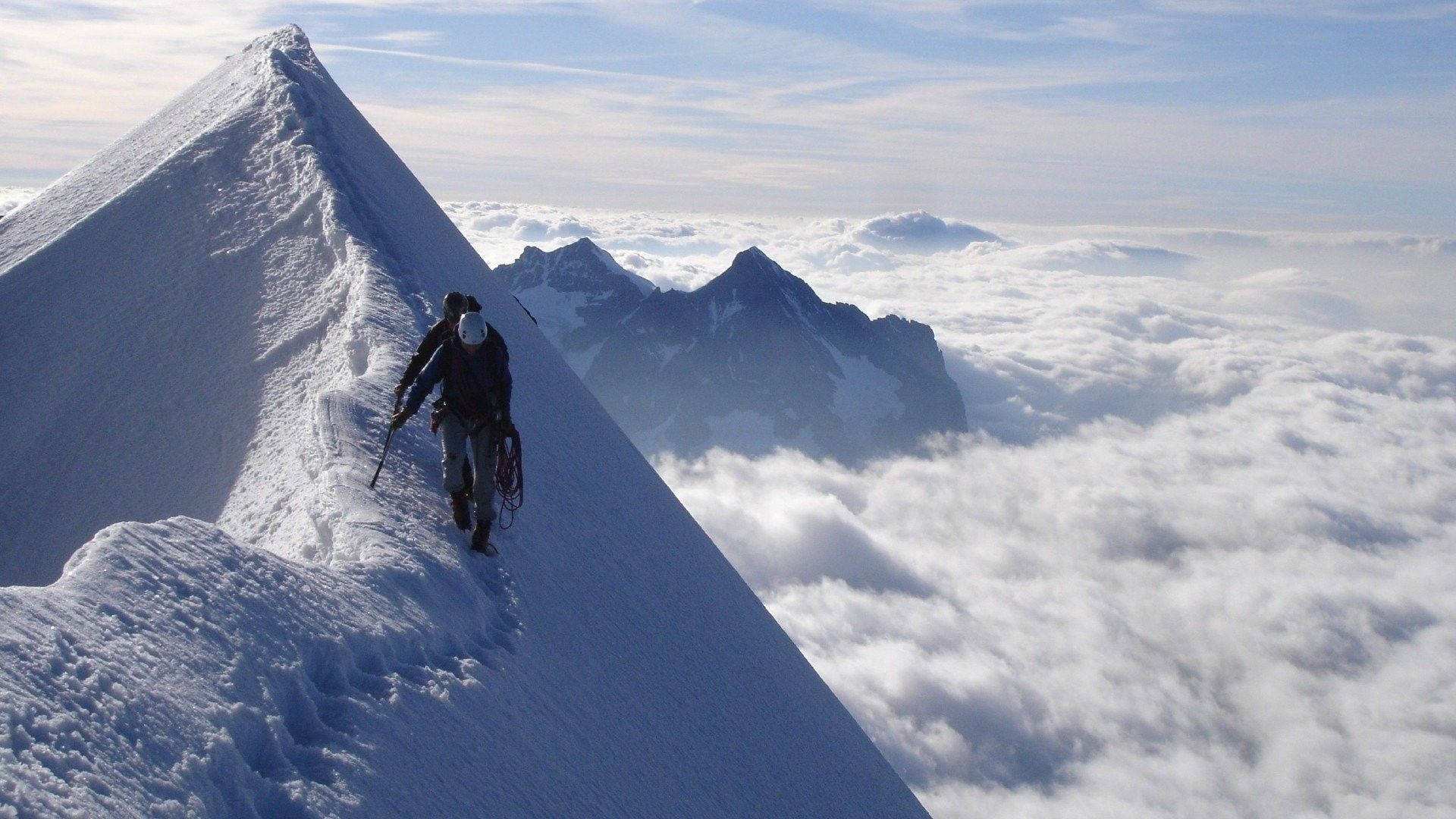 登山者攀登雲海之上積雪的山峰