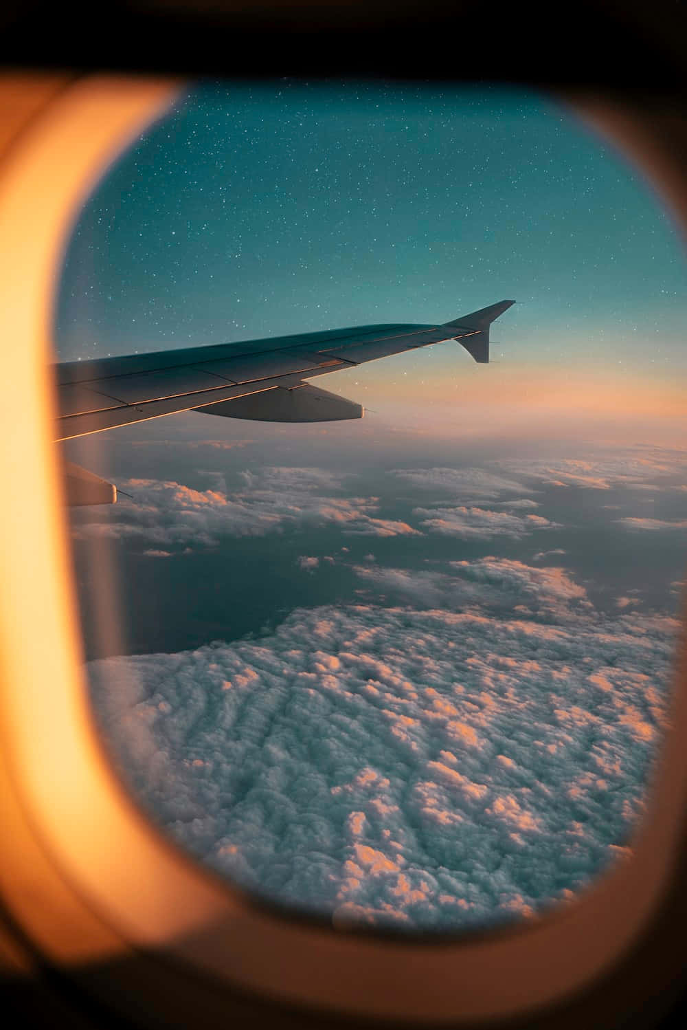 雲端之旅 壁紙 — 透過飛機窗戶看到的飛機機翼，黃昏時分，星空和下方發光的雲層。