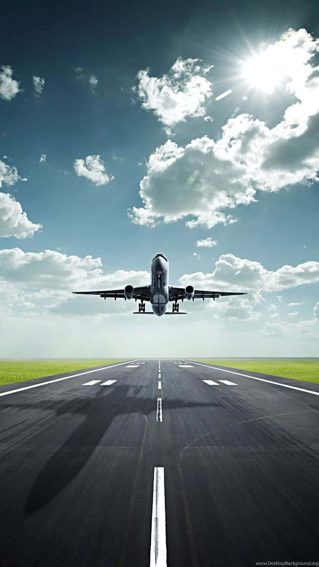 雲端觀光 壁紙 — 一架商用飛機在陽光普照、雲朵散佈的天空下從跑道上升起。