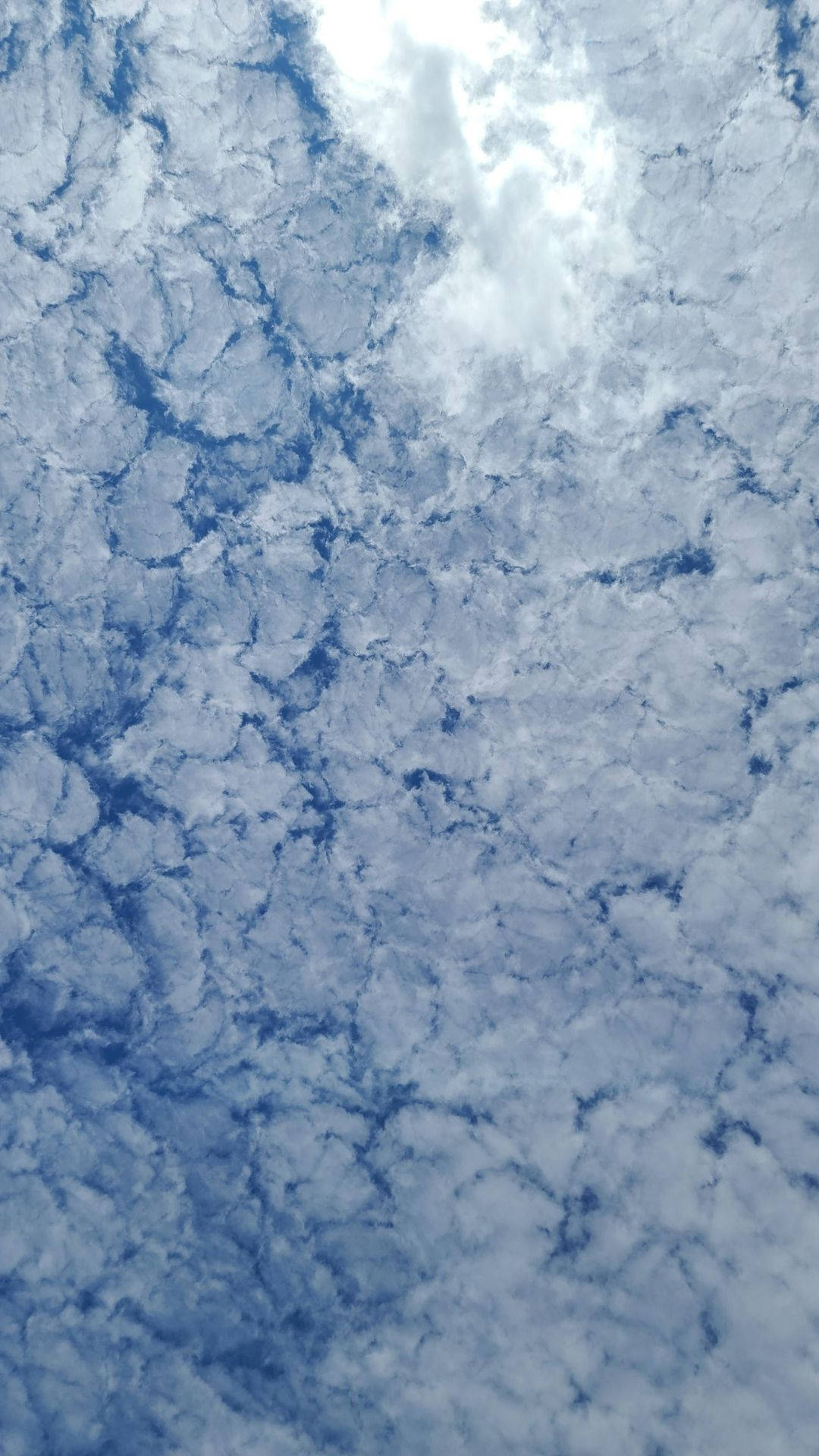 雲覆天際 壁紙 — 一張特寫照片，展示紋理豐富的藍白雲朵在廣闊天空中旋轉。