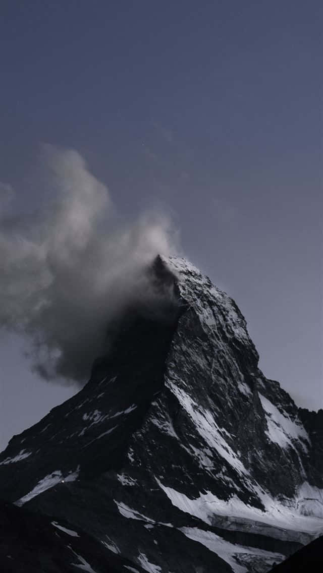 一座白雪覆蓋的山峰，雲霧在山頂周圍旋轉。