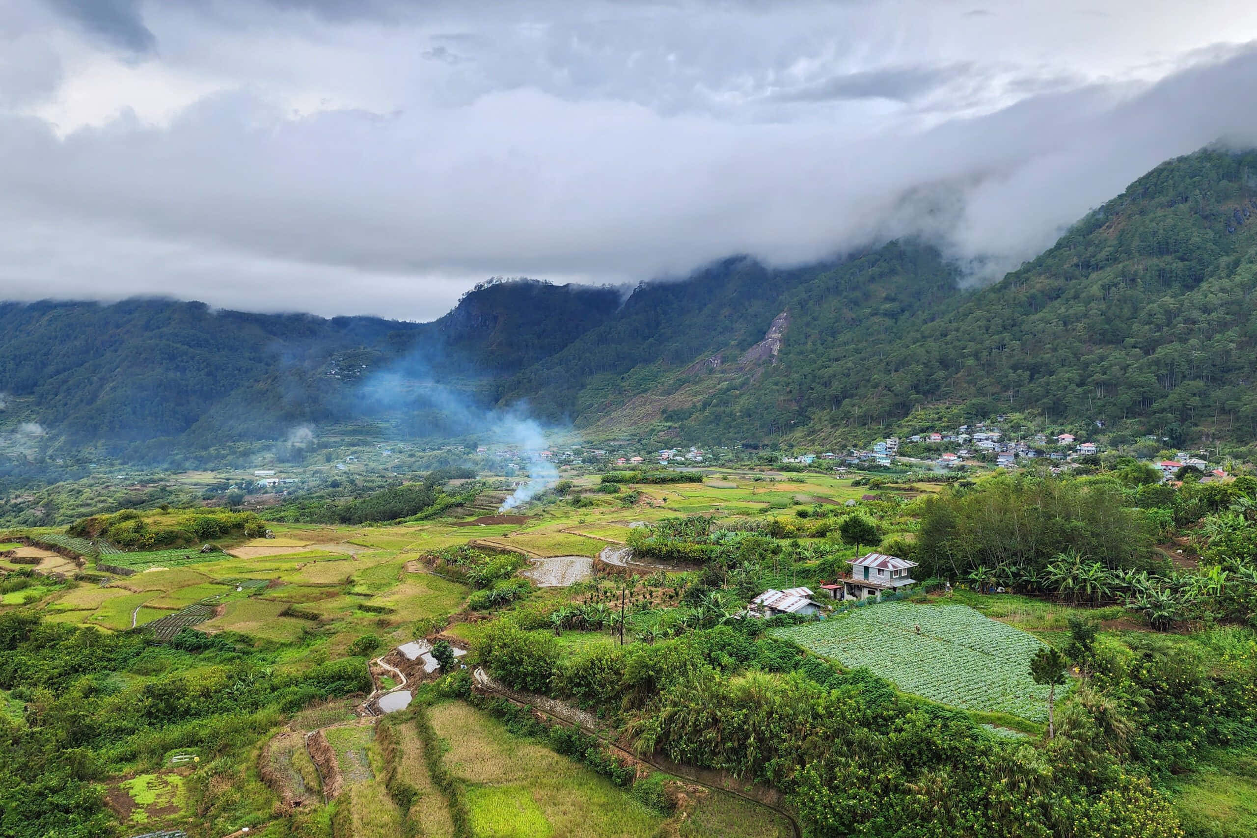 Green Landscape 桌布 壁紙 — 雲霧繚繞的山谷，梯田和小村莊坐落在鬱鬱蔥蔥的青山之間，天空多雲。