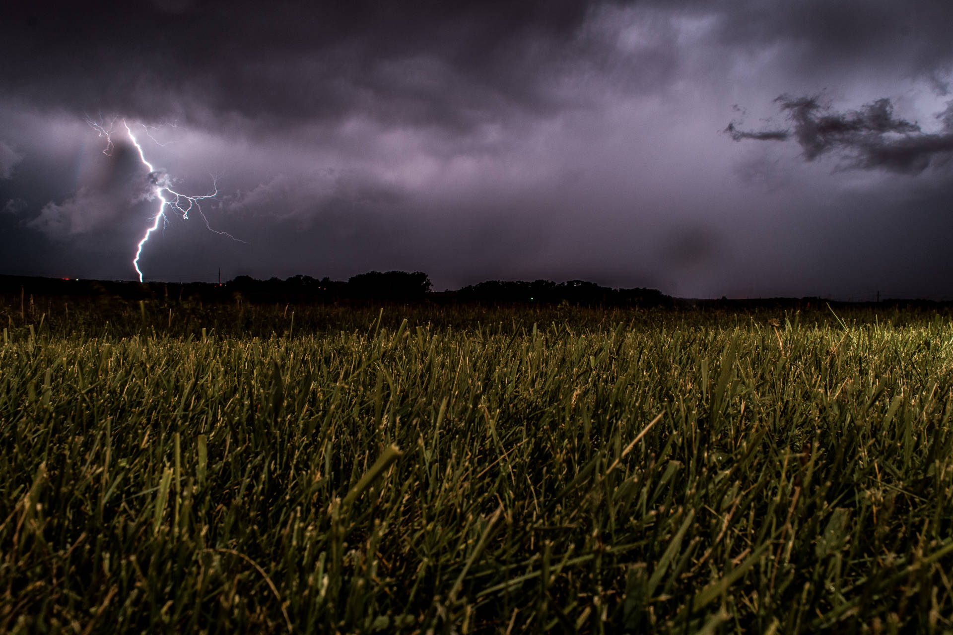 閃電擊中草地，背景是暴風雨的夜空。