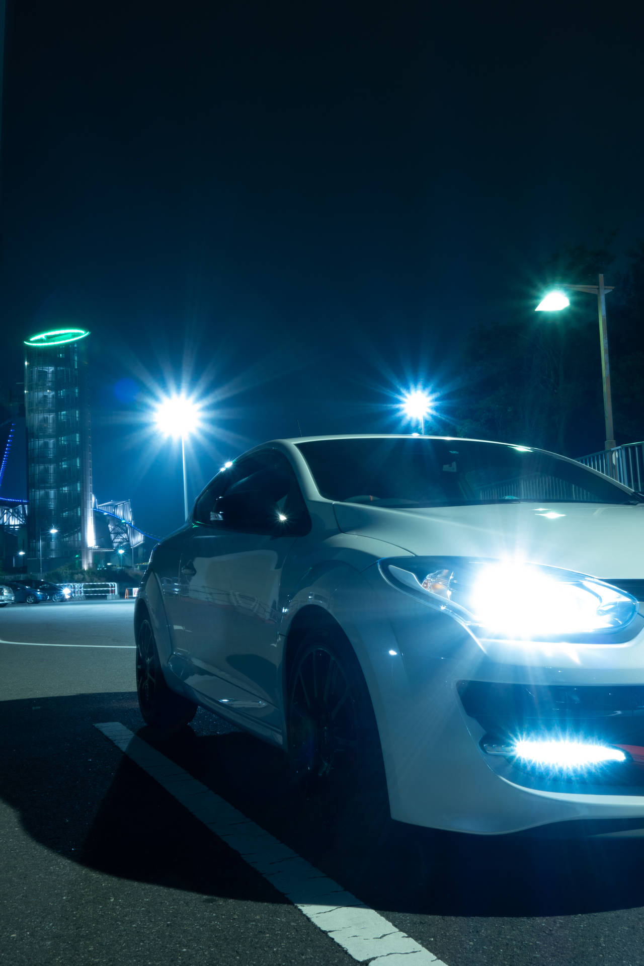 白色跑車停在夜晚的城市街道上，車頭燈和街燈明亮。
