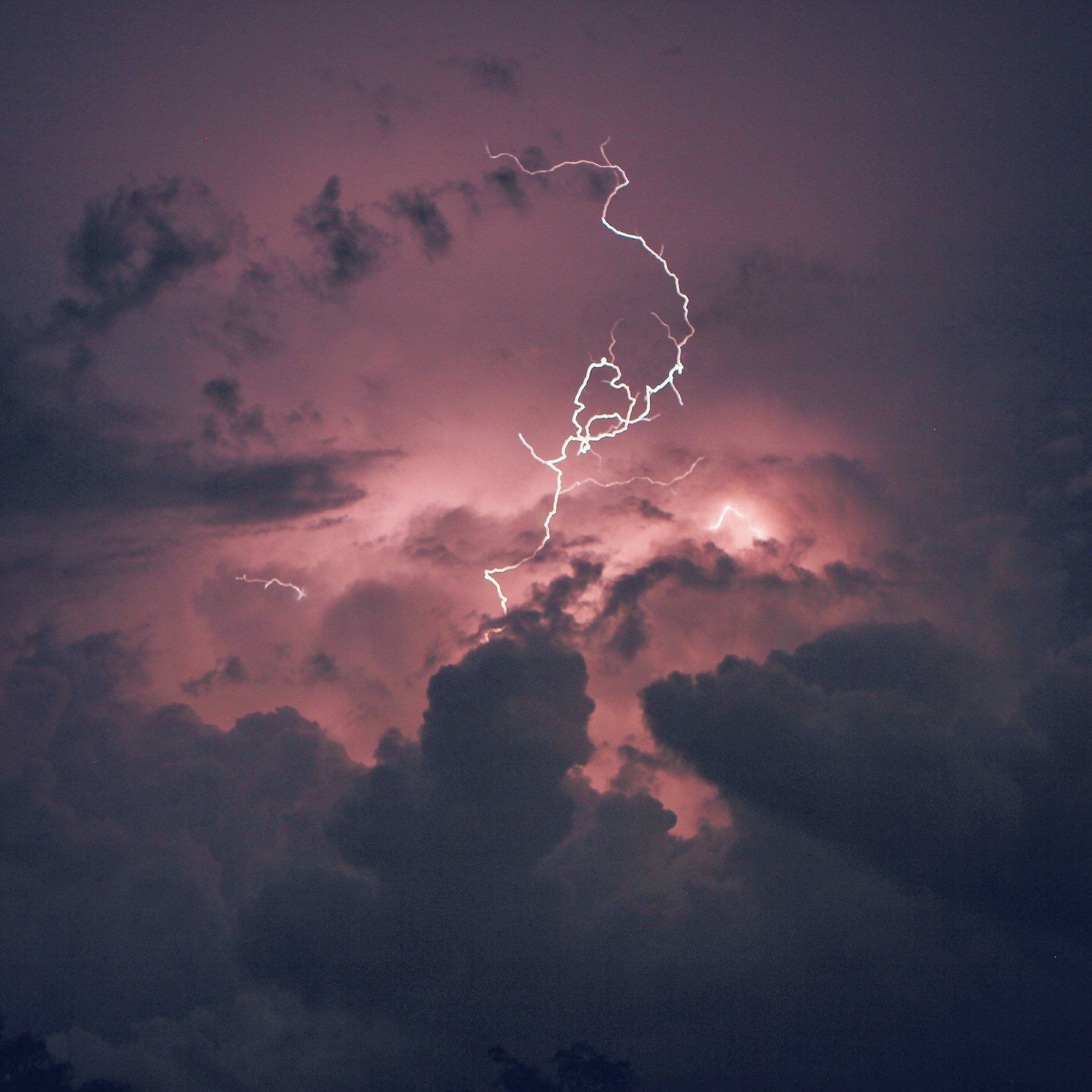 一道強大的閃電照亮了暴風雨的紫色天空。
