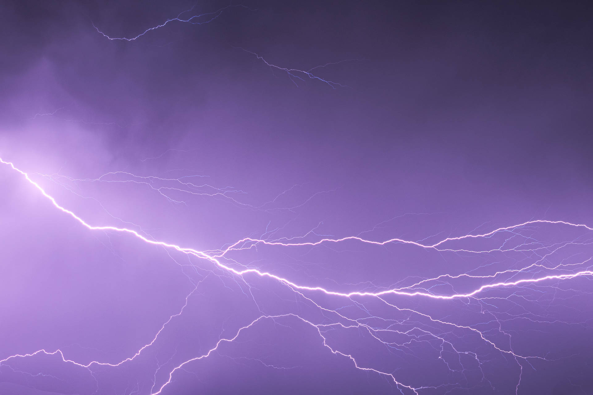 紫色暴風雨天空，明亮的閃電照亮雲層。