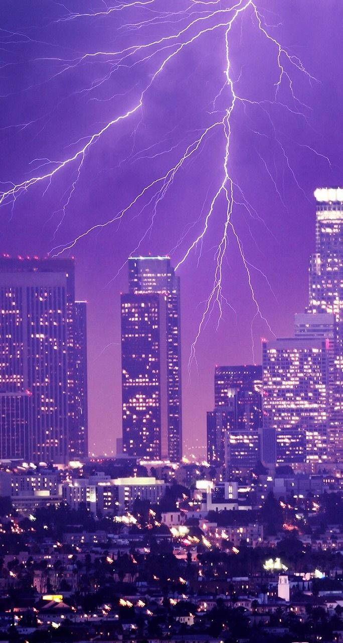 紫色閃電照亮夜晚的城市天際線和明亮的建築物。