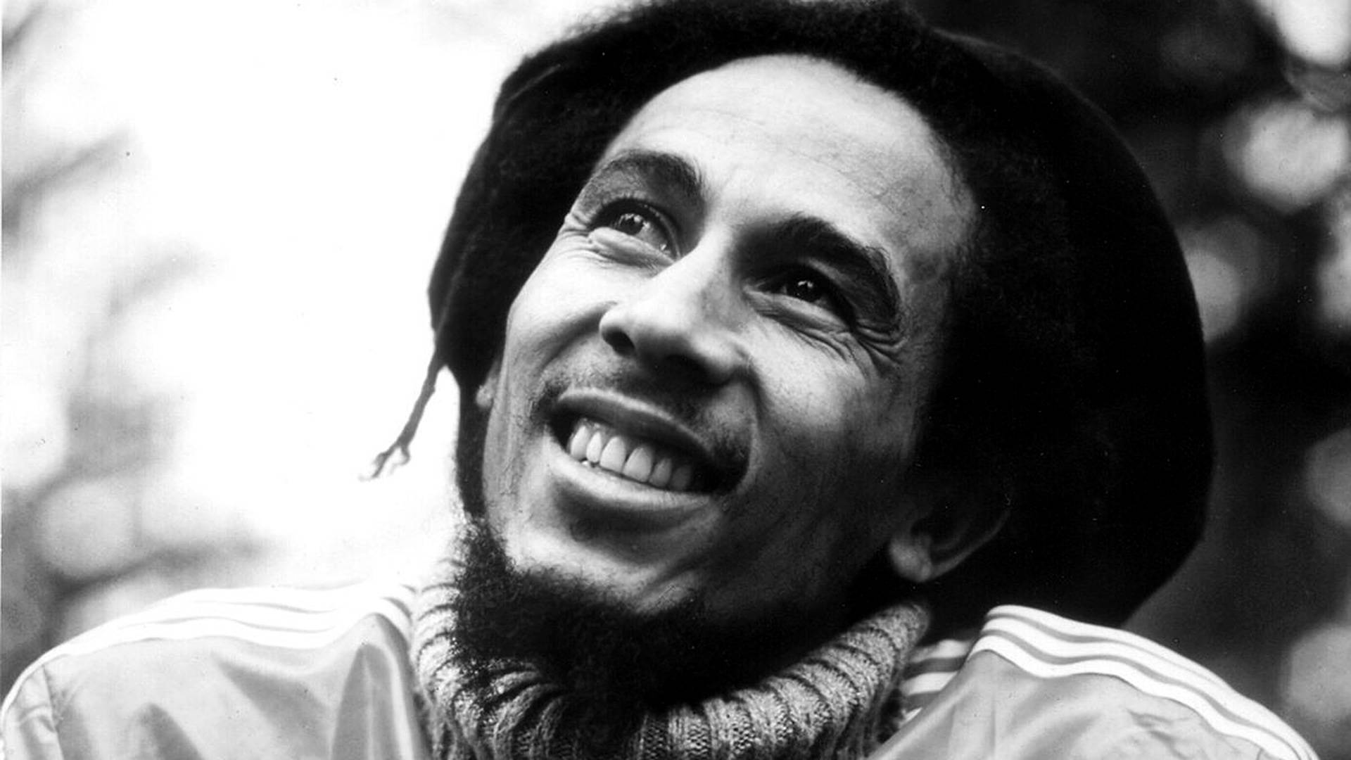 Bob Marley 帶著辮子和 Adidas 外套在戶外微笑。