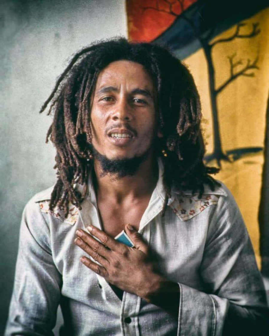 雷鬼傳奇——鮑勃·馬利 壁紙 — Bob Marley 梳著雷鬼辮，手放在胸前，背景係色彩繽紛嘅塗鴉。