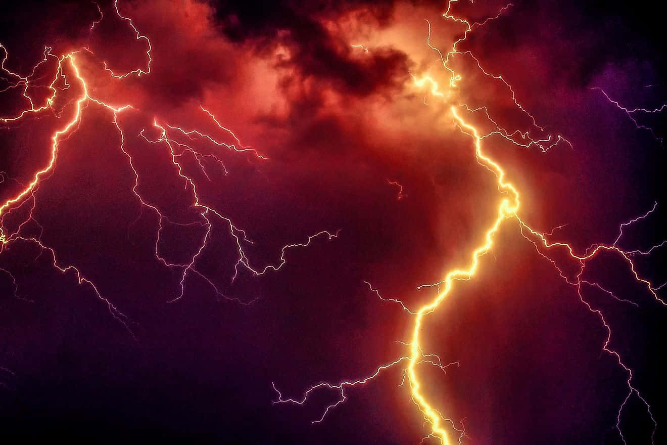 強烈的閃電照亮了帶有紅色和紫色雲層的黑暗暴風雨天空。
