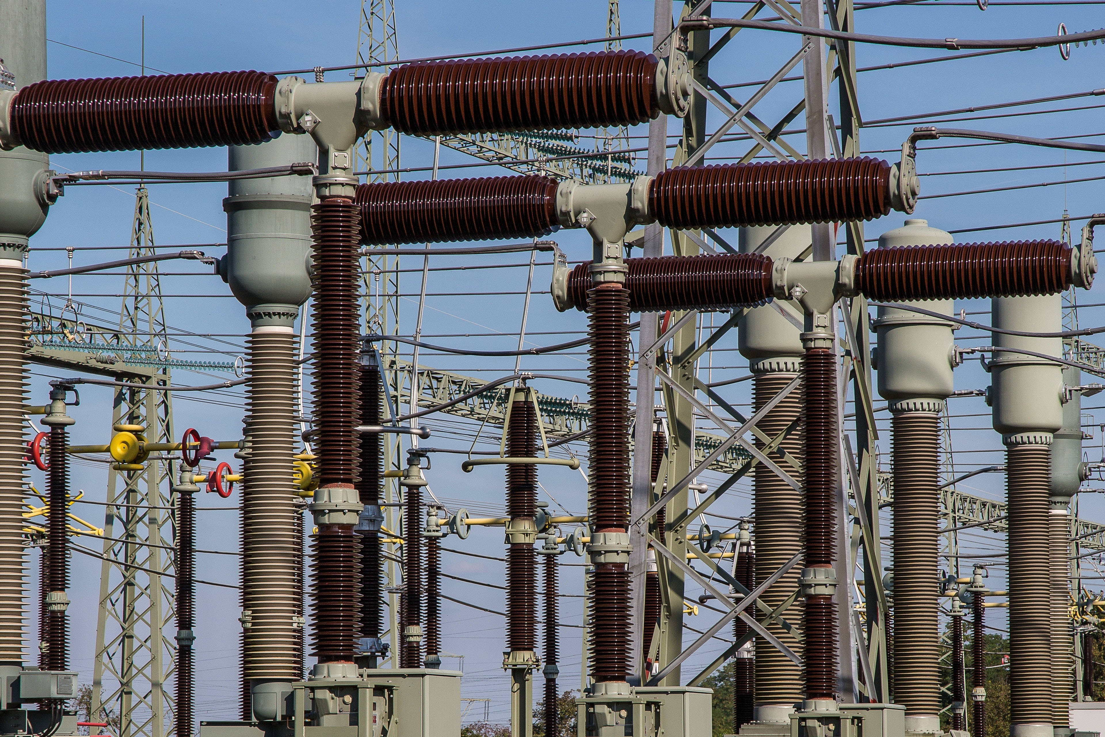 電力發電廠 壁紙 — 工業電力變壓器嘅特寫，帶有栗色絕緣體，背景係晴朗嘅藍天。