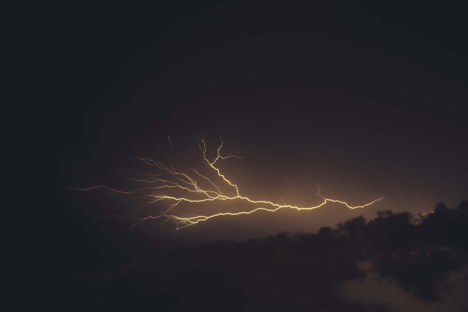 一道強勁的閃電照亮了暴風雨的夜空，伴隨著烏雲。