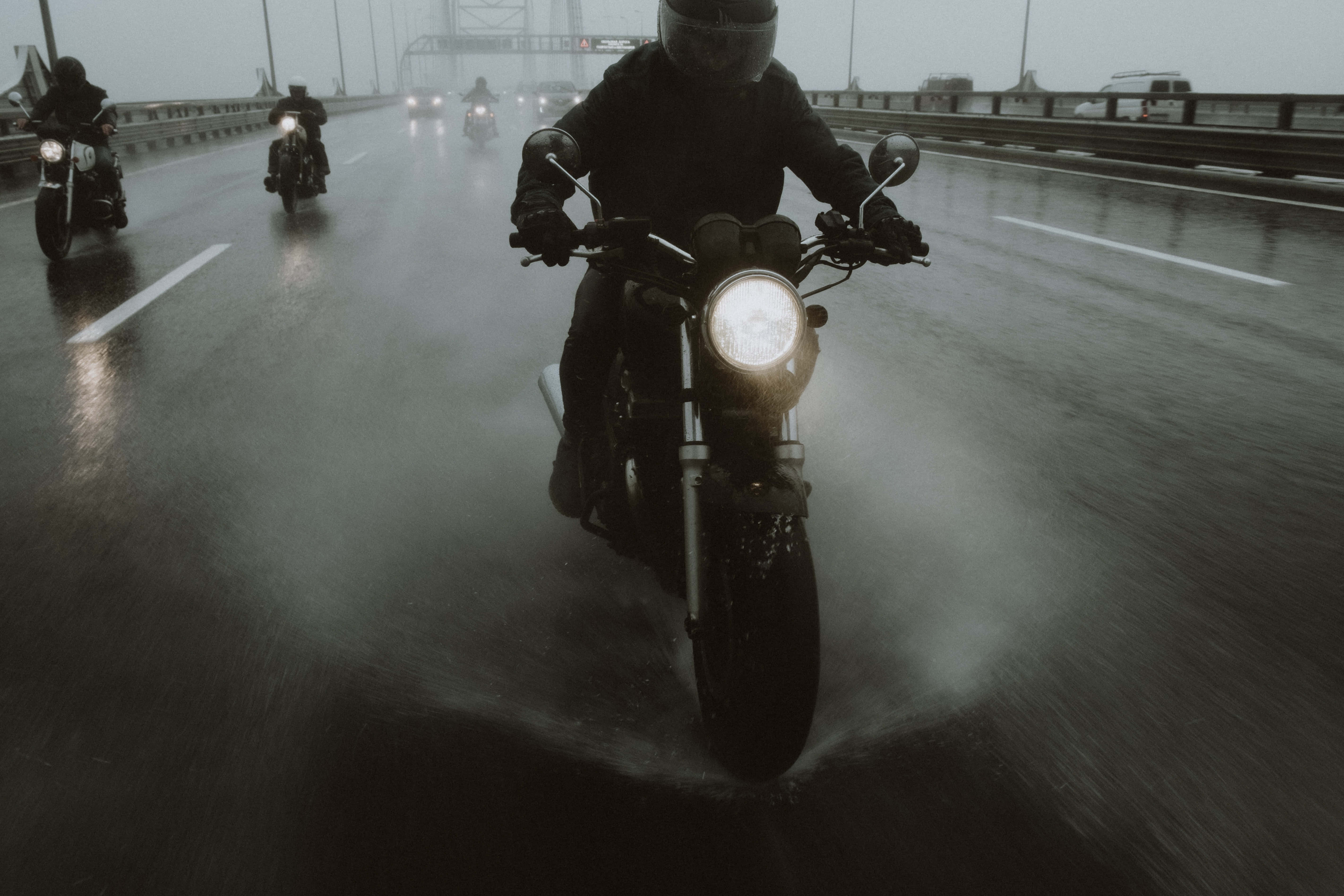 road trip 桌布 壁紙 — 電單車手在滂沱大雨中行駛在濕滑的高速公路上，車頭燈劃破迷霧籠罩的昏暗。