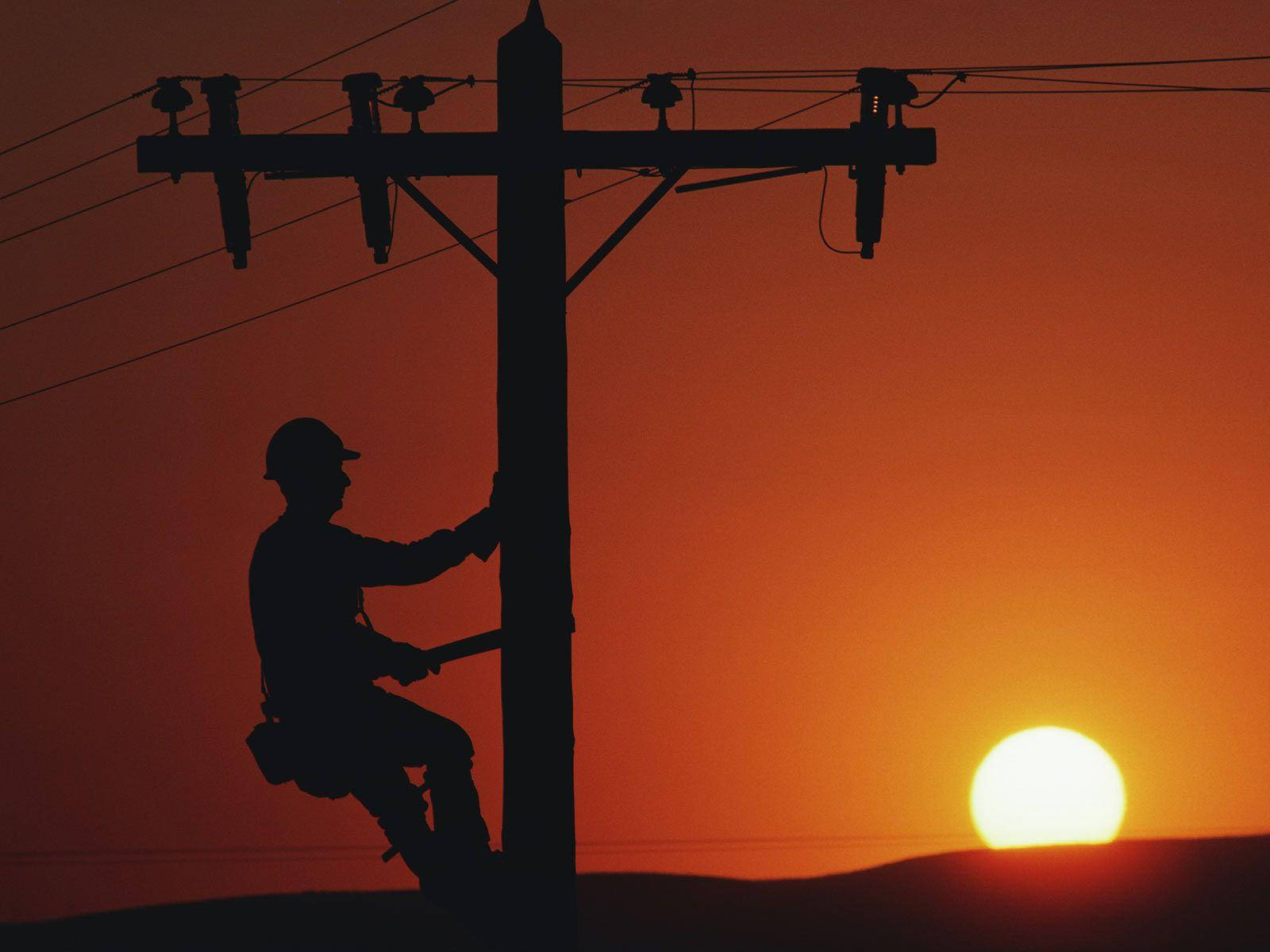 電工攀爬電柱 壁紙 — 一名電線工人爬上電線桿的剪影，背景是火紅的橙色夕陽和低垂的太陽。