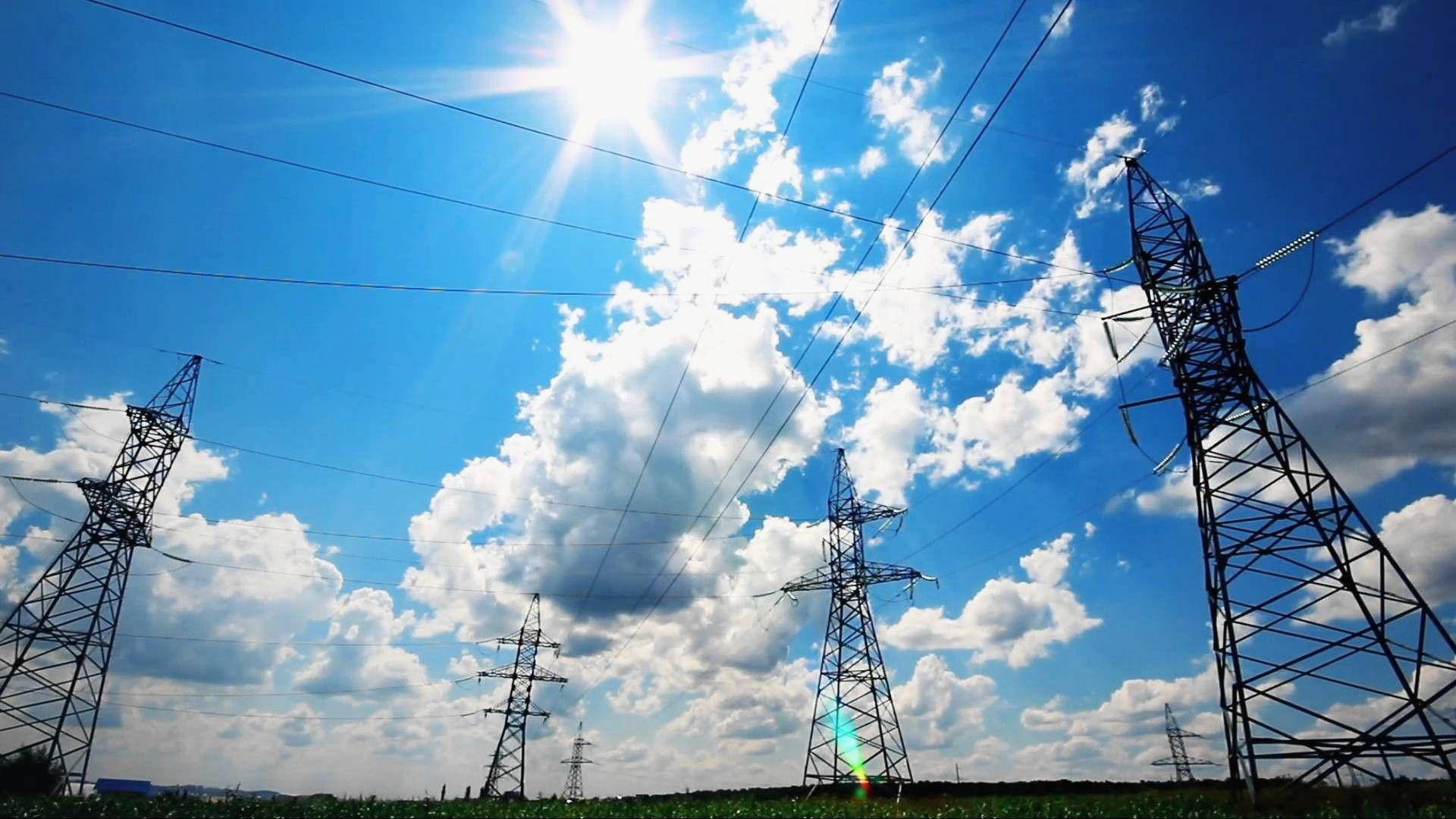 電工電塔 壁紙 — 高聳的電塔在熾熱的太陽下，橫跨點綴著蓬鬆白雲的鮮豔藍天。