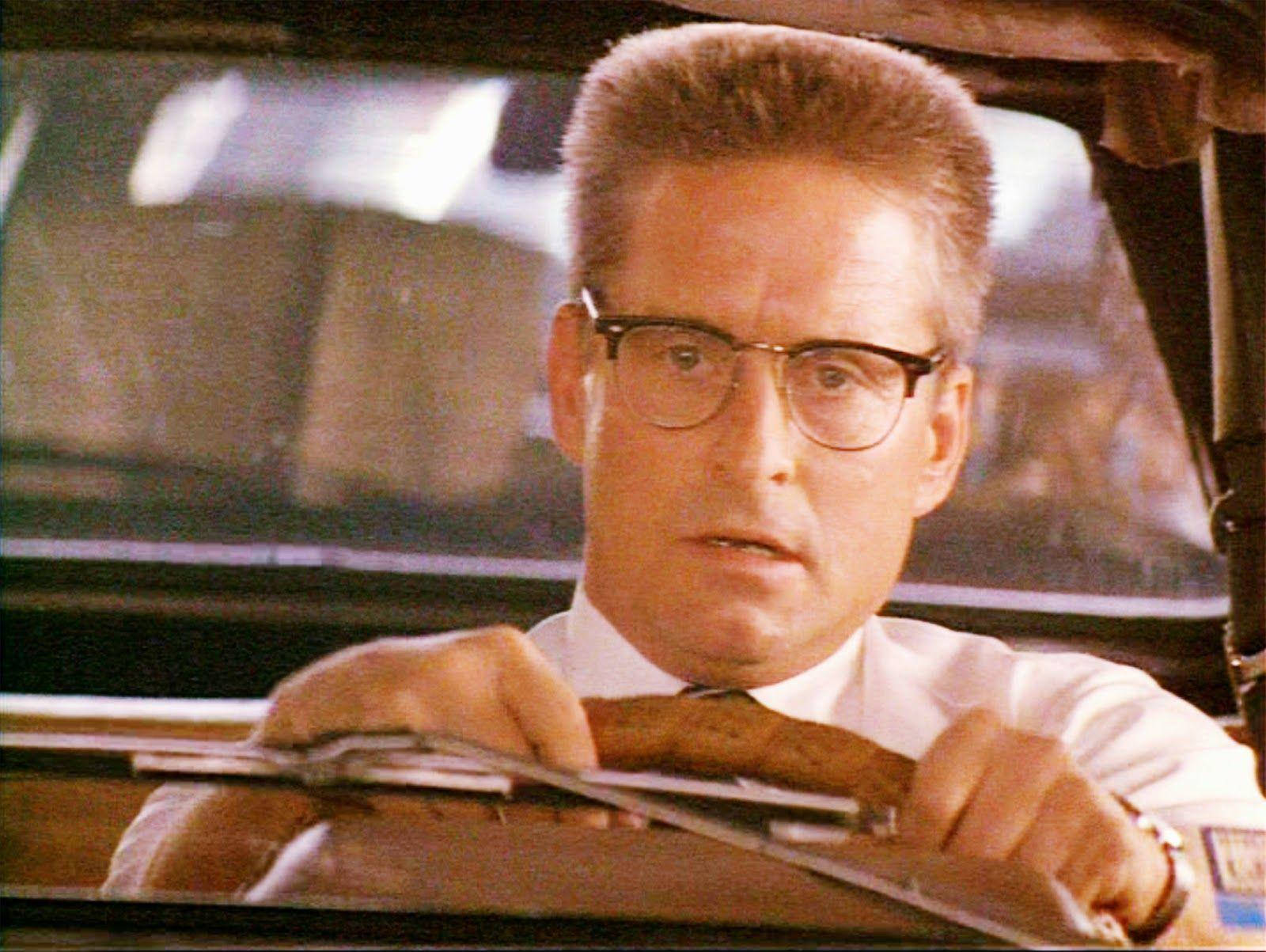 電影《Falling Down》中的演員邁克爾·道格拉斯 壁紙 — 一名戴眼鏡、身穿白恤衫的男子，神情專注地握著一輛復古車的方向盤。