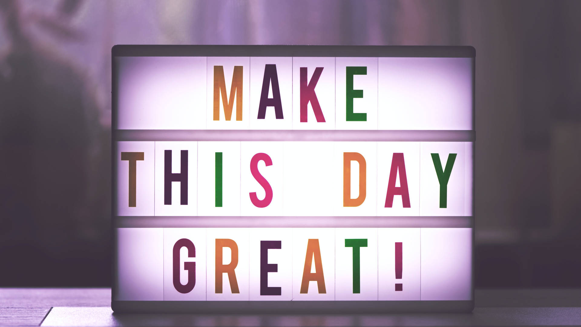 一個彩色燈箱標誌，上面寫著「MAKE THIS DAY GREAT!」