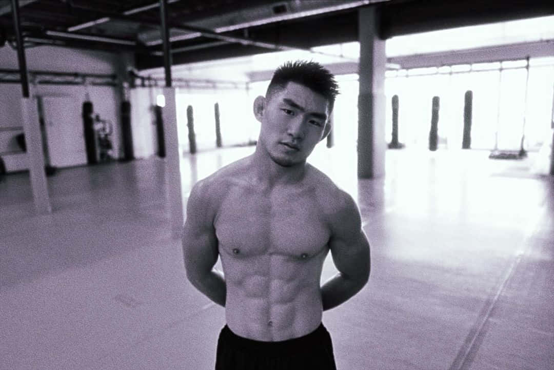 一個肌肉發達的男人在健身房，有明顯的腹肌和嚴肅的表情。