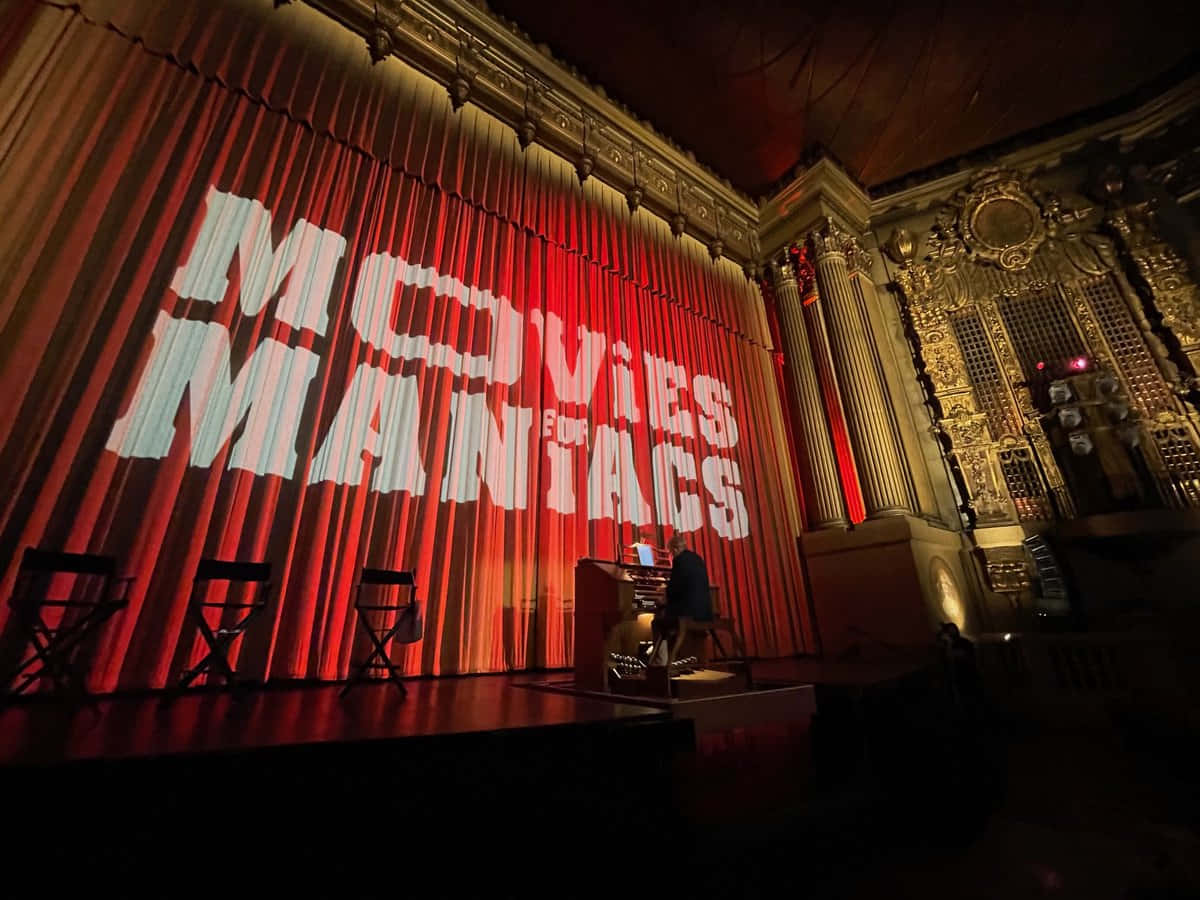 在寫有Movies Maniacs的紅色帷幕劇院舞台上彈鋼琴的人。