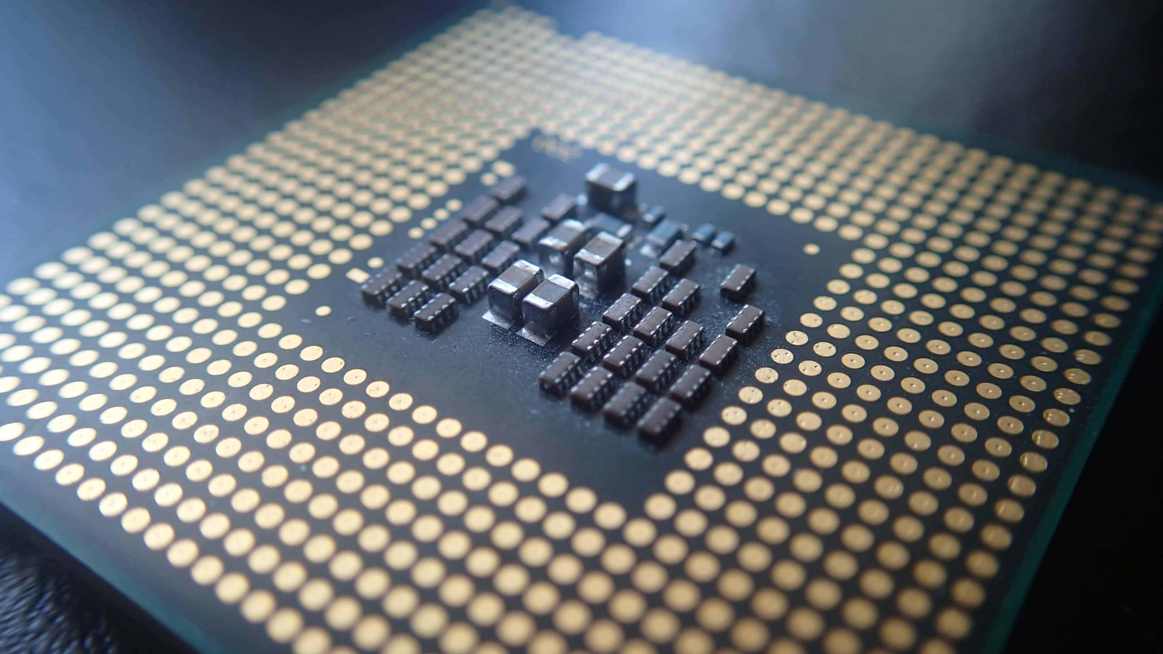 4K Processor 桌布 壁紙 — 電腦處理器晶片特寫，金色引腳和黑色集成電路，在戲劇性燈光下。