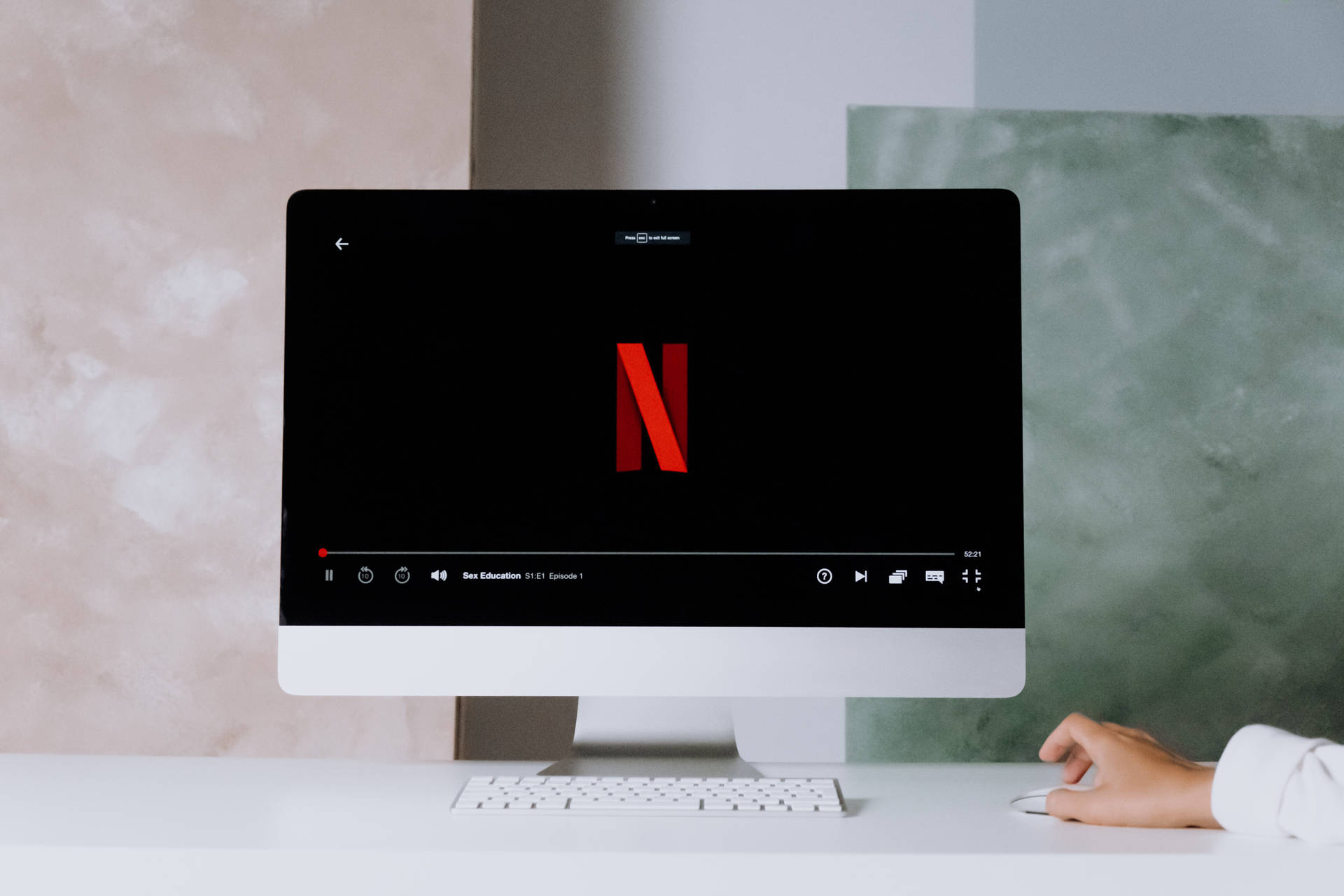 手使用滑鼠在現代 iMac 電腦上串流 Netflix。