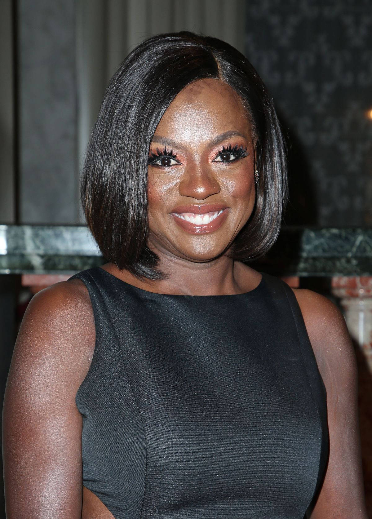 電視劇《How to Get Away with Murder》女主角維奧拉·戴維斯 壁紙 — 一位擁有光滑鮑伯頭和濃密睫毛的耀眼女性，穿著黑色無袖連衣裙，溫暖地微笑。