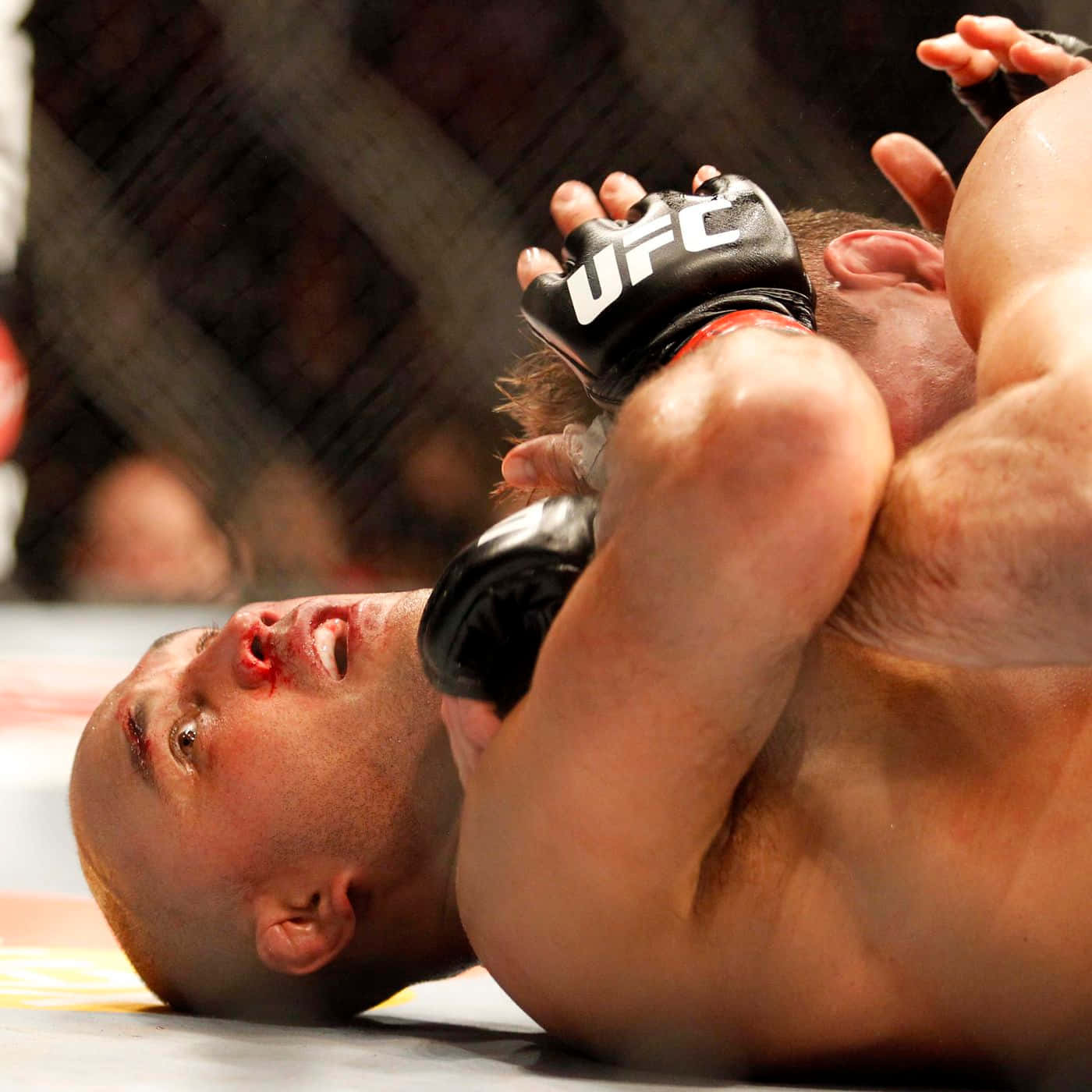 UFC拳手在激烈的MMA比賽中被鎖在墊子上，臉上帶血