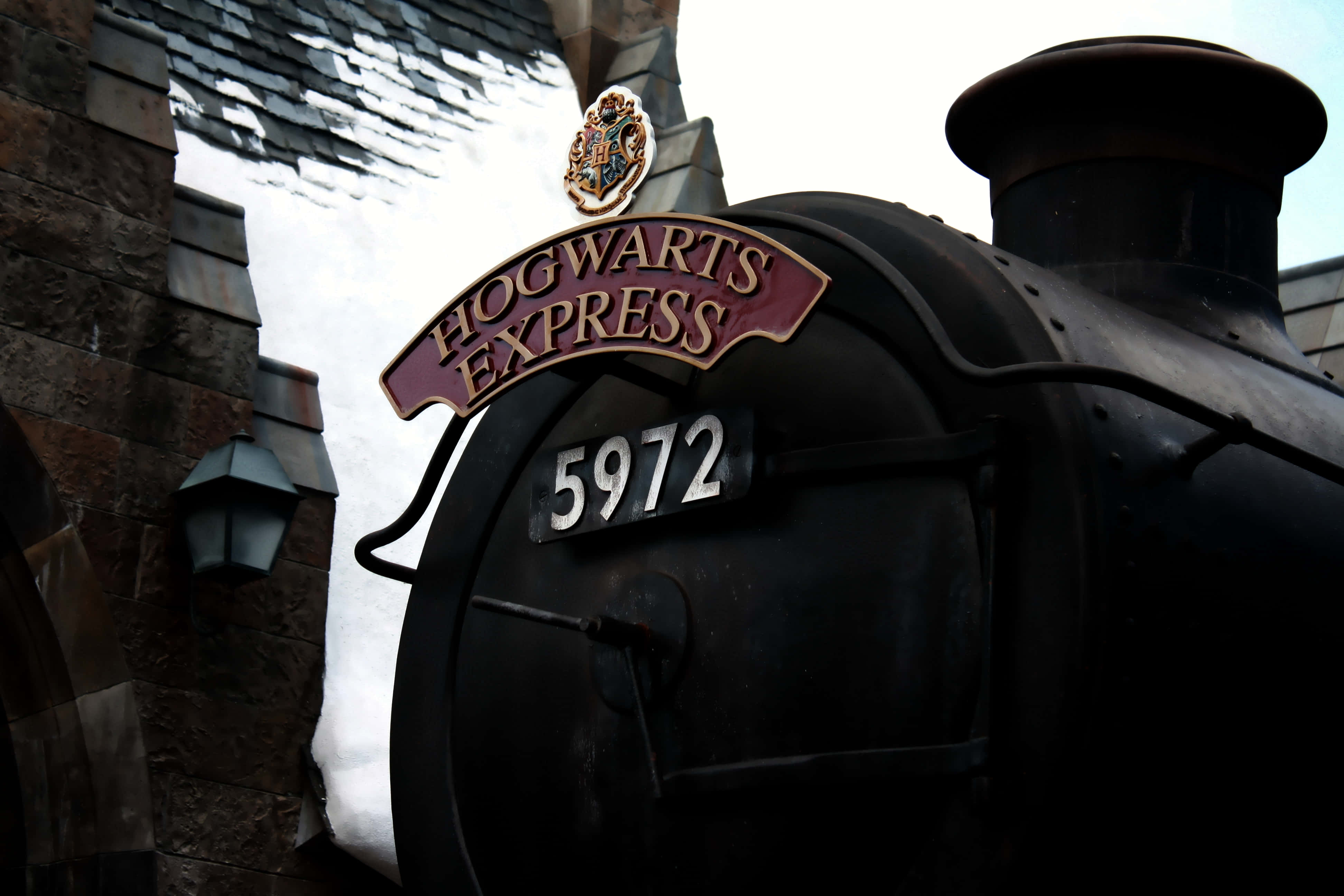 Platform 9 3/4 桌布 壁紙 — 霍格華茲特快蒸汽火車的特寫，帶有其標誌性的栗色標誌和編號5972，背景為石頭建築。