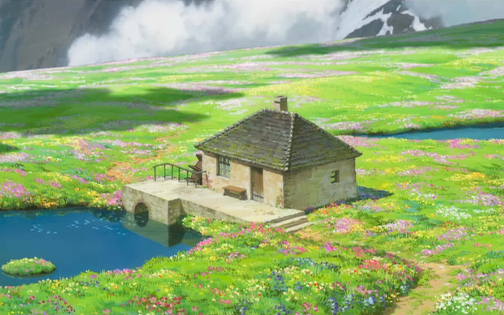 《霍爾的移動城堡》的奇景 壁紙 — 一間古雅的石頭小屋坐落在平靜的藍色池塘旁，周圍是充滿活力的野花，天空多雲。